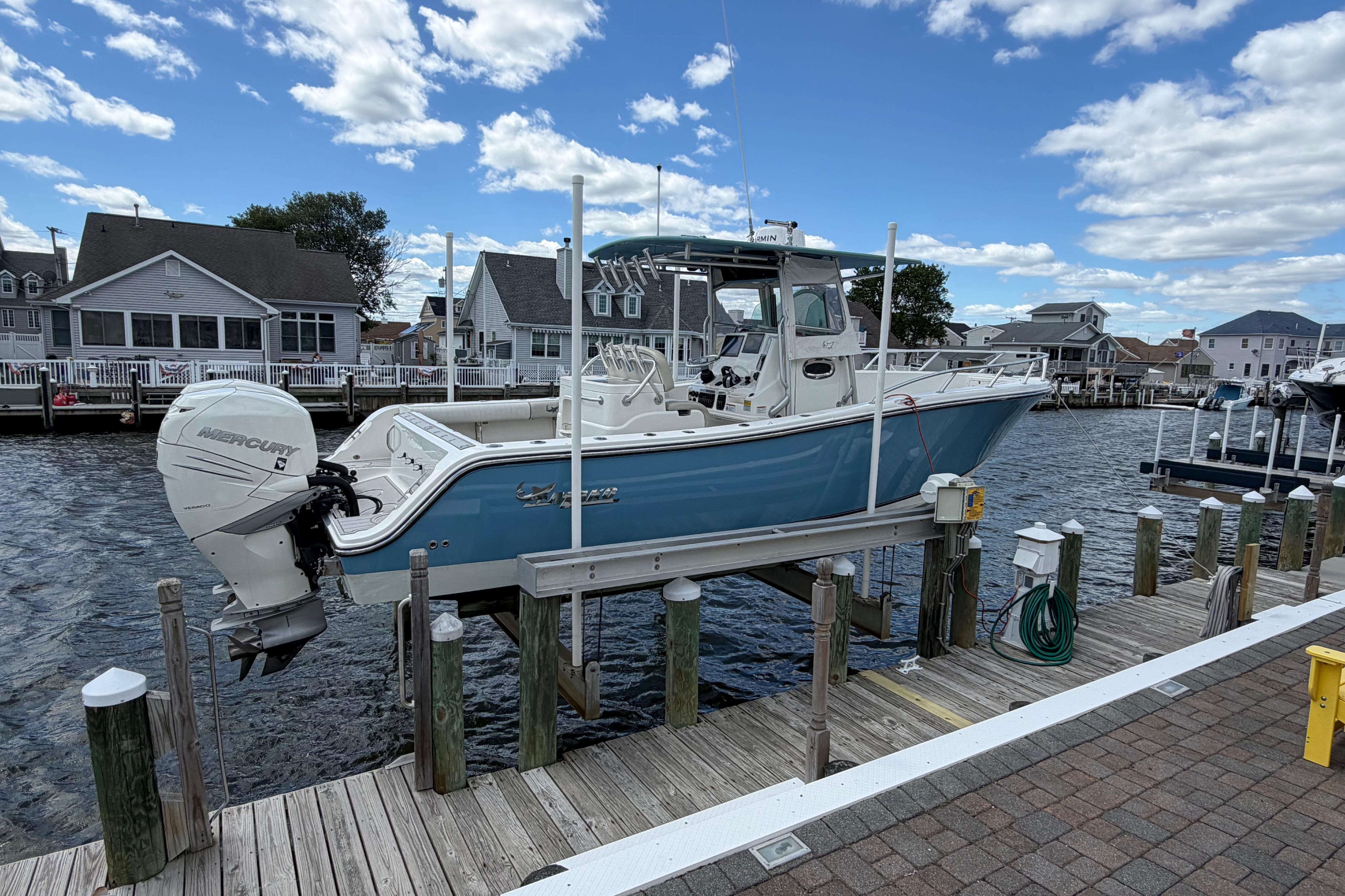 2017 Mako 284 Center Console boat docked, featuring a Mercury engine, under a clear blue sky.