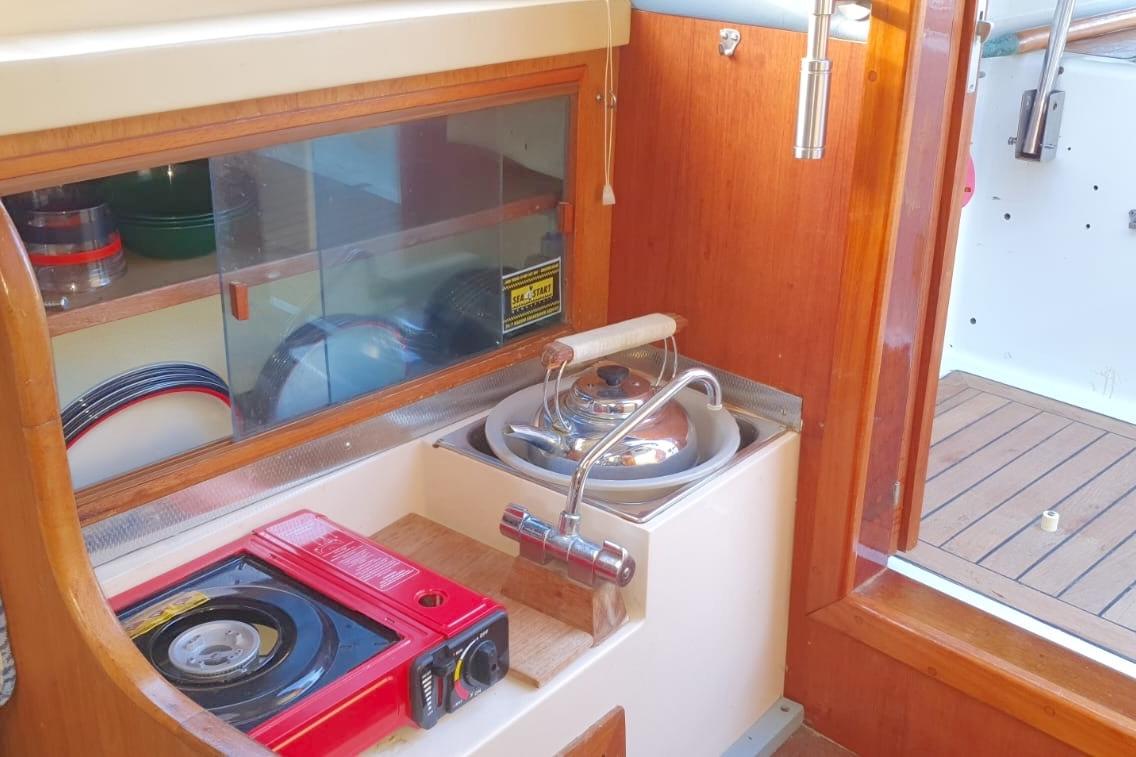 Compact galley kitchen in 1989 Fairey Spearfish MKIII boat with stove and sink.