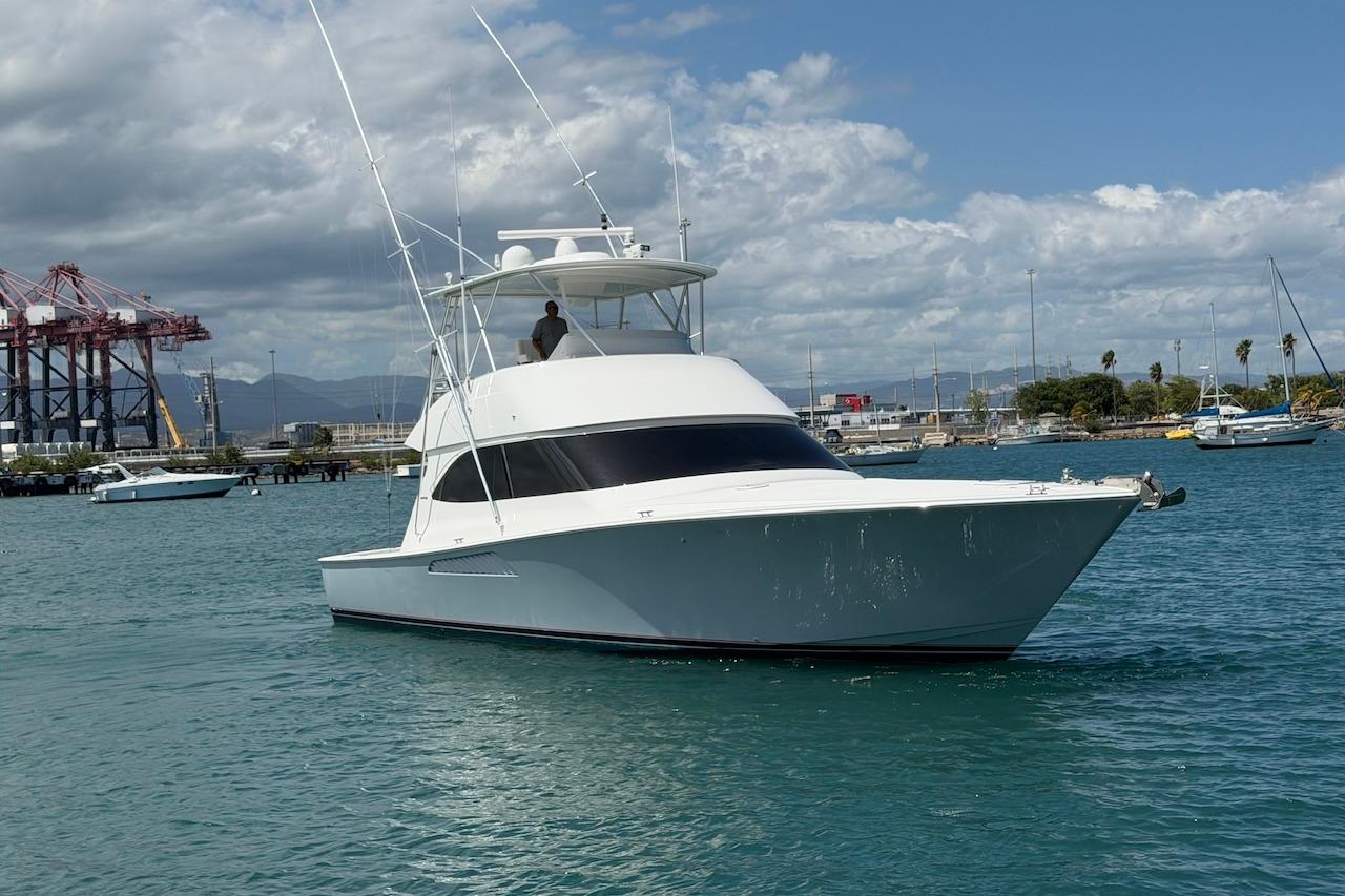 2012 Viking 50 Convertible yacht cruising in a harbor with a scenic backdrop.