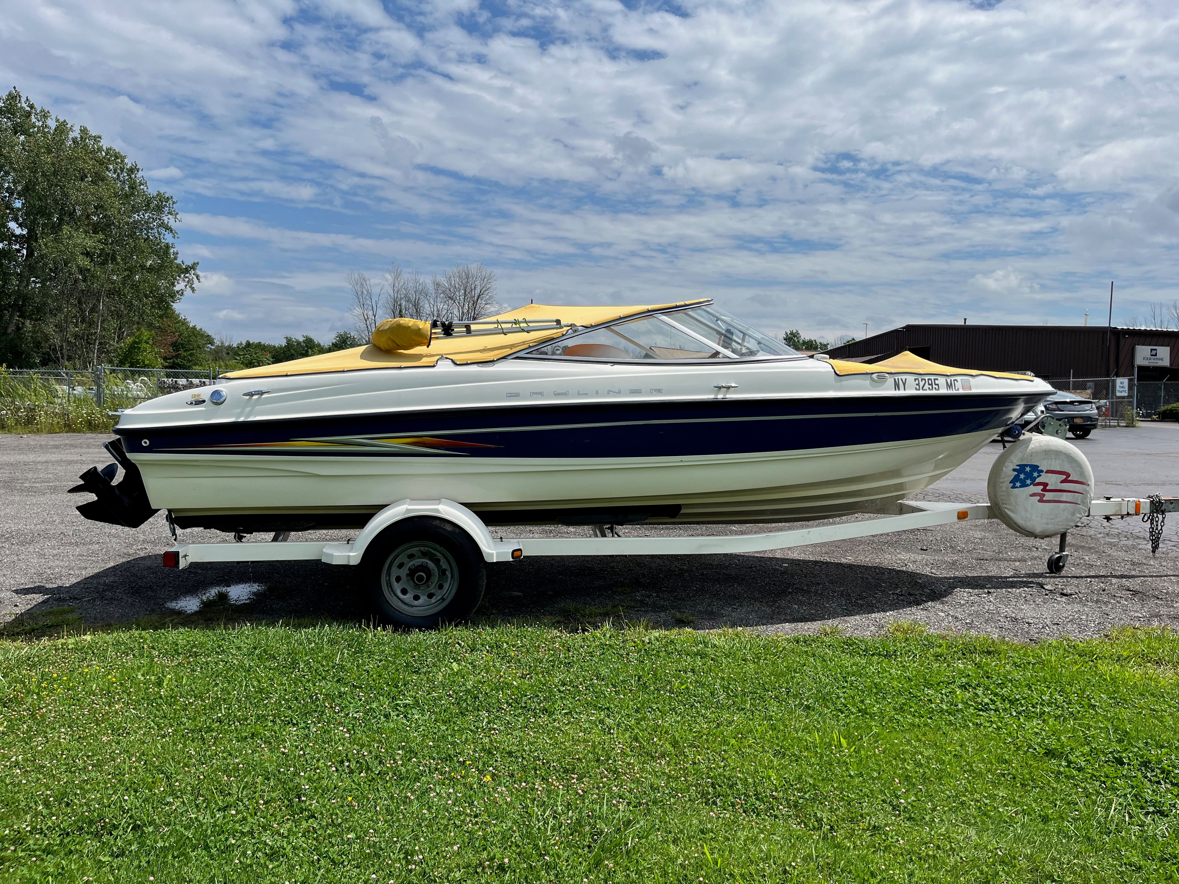 2005 Bayliner 205BR on a trailer, with a yellow cover, parked on a lot.