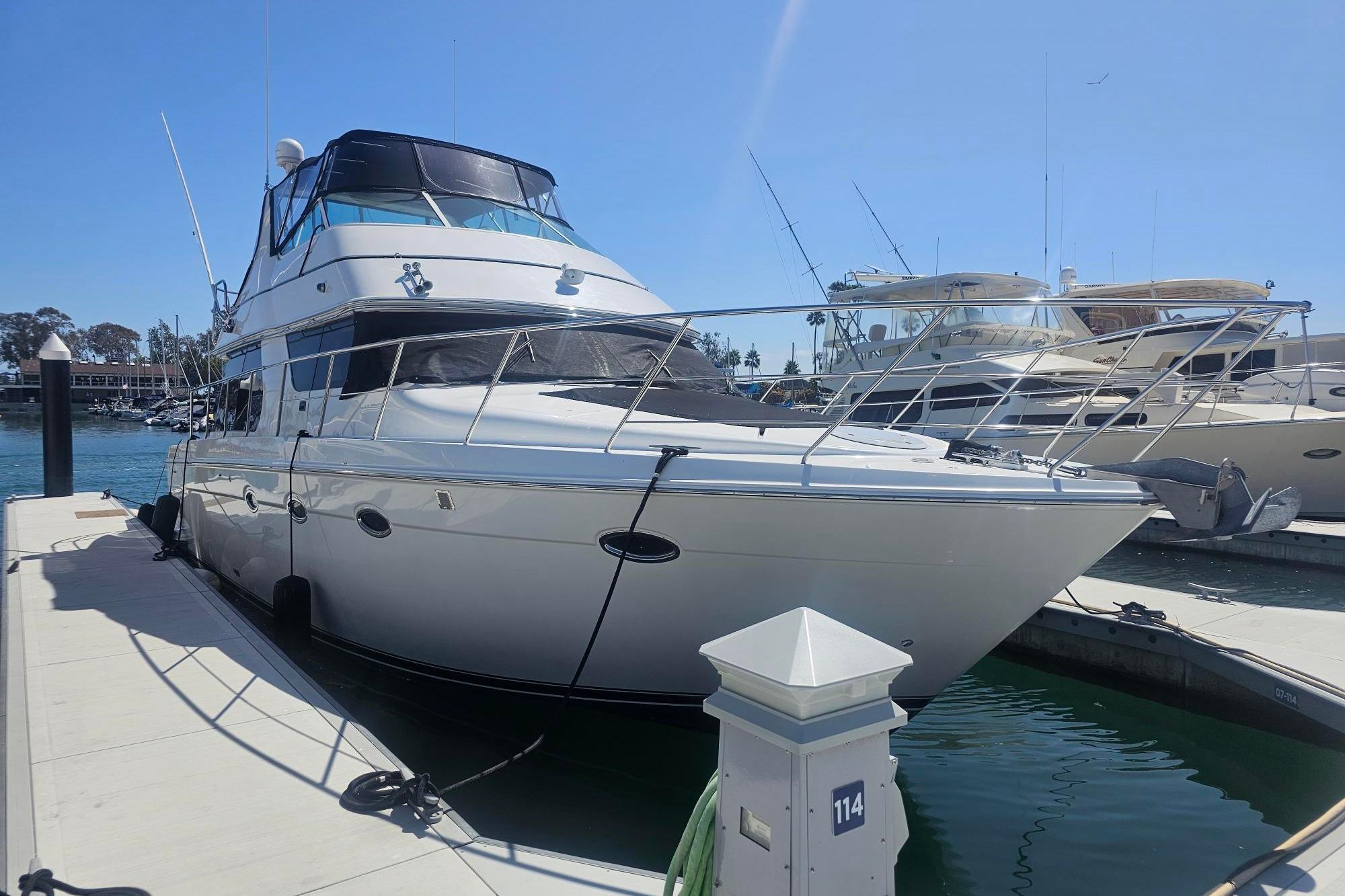 2002 Carver 450 Voyager Pilothouse yacht docked at marina under clear blue sky.