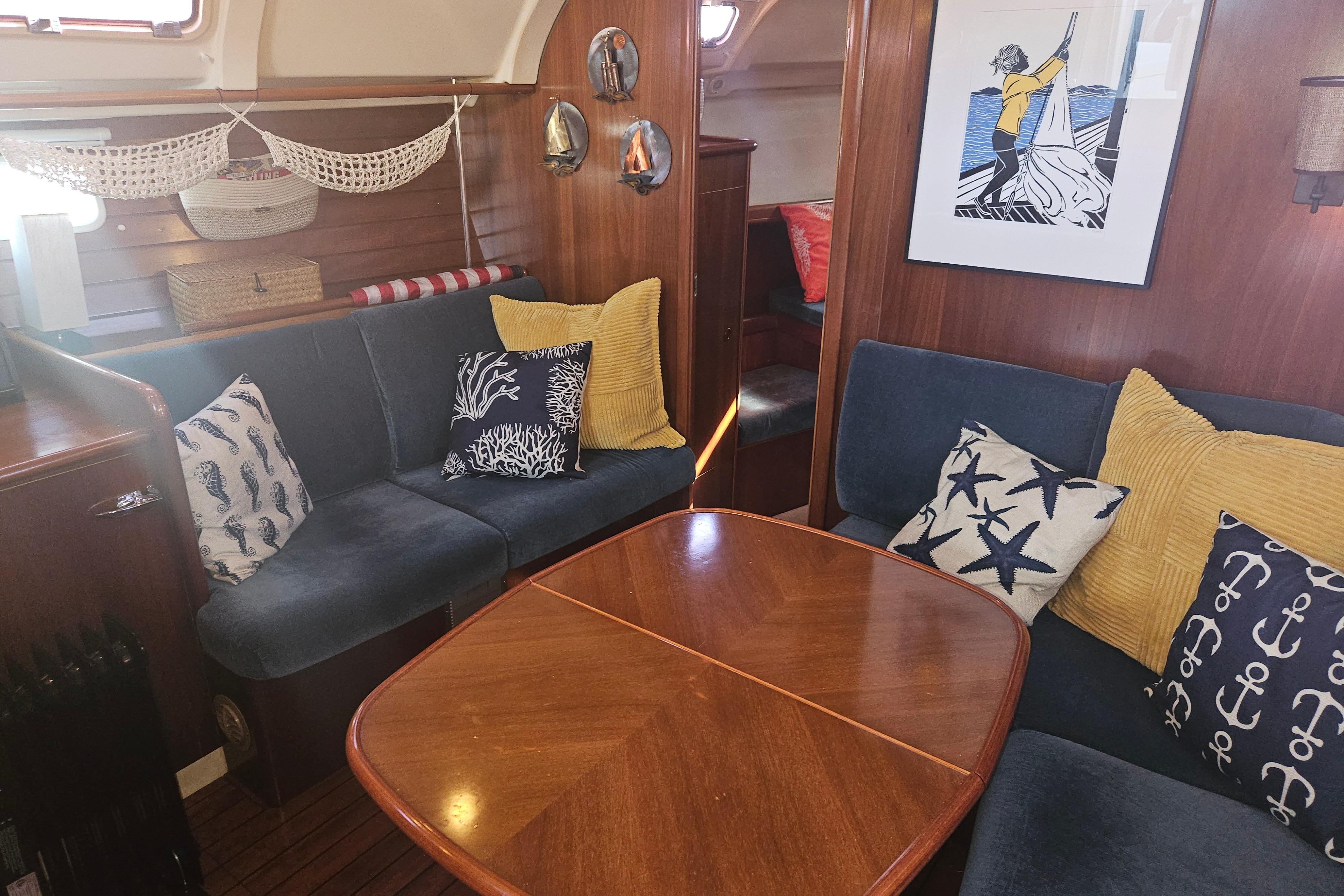 Cozy interior of 1998 Beneteau 381 sailboat with nautical-themed decor and wooden furnishings.