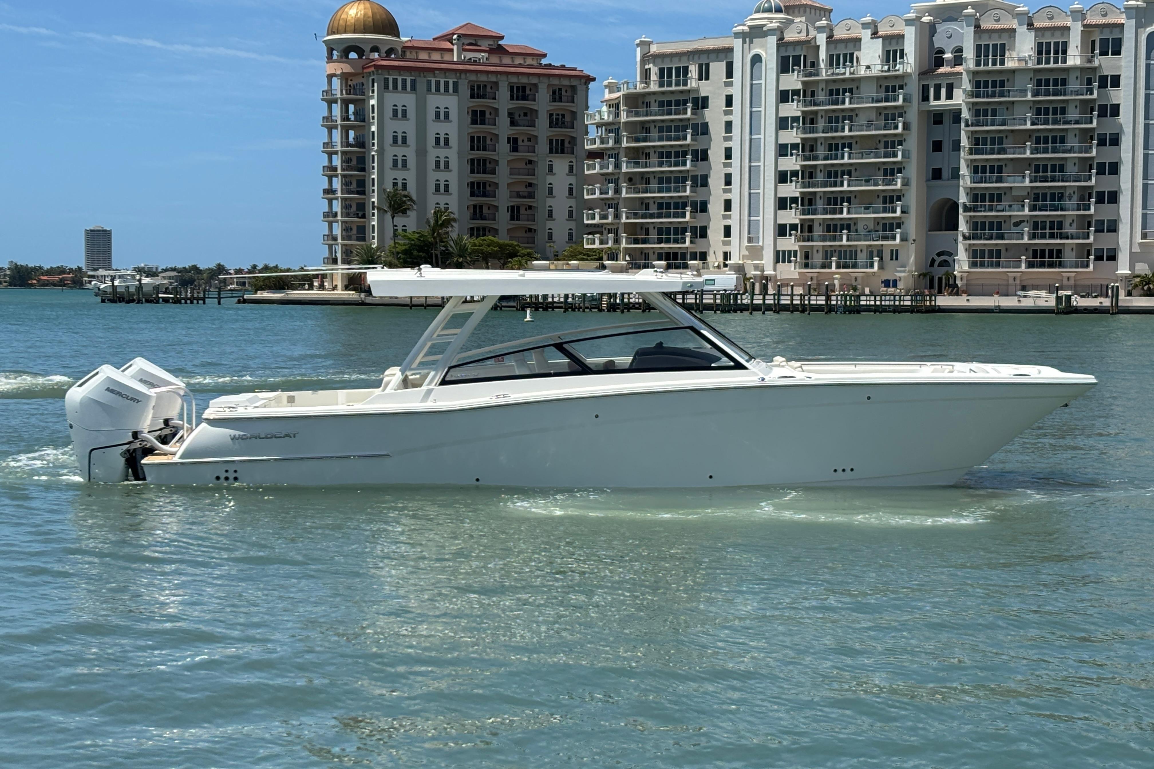 2026 World Cat 400 DC-X Island boat cruising near luxury waterfront buildings.