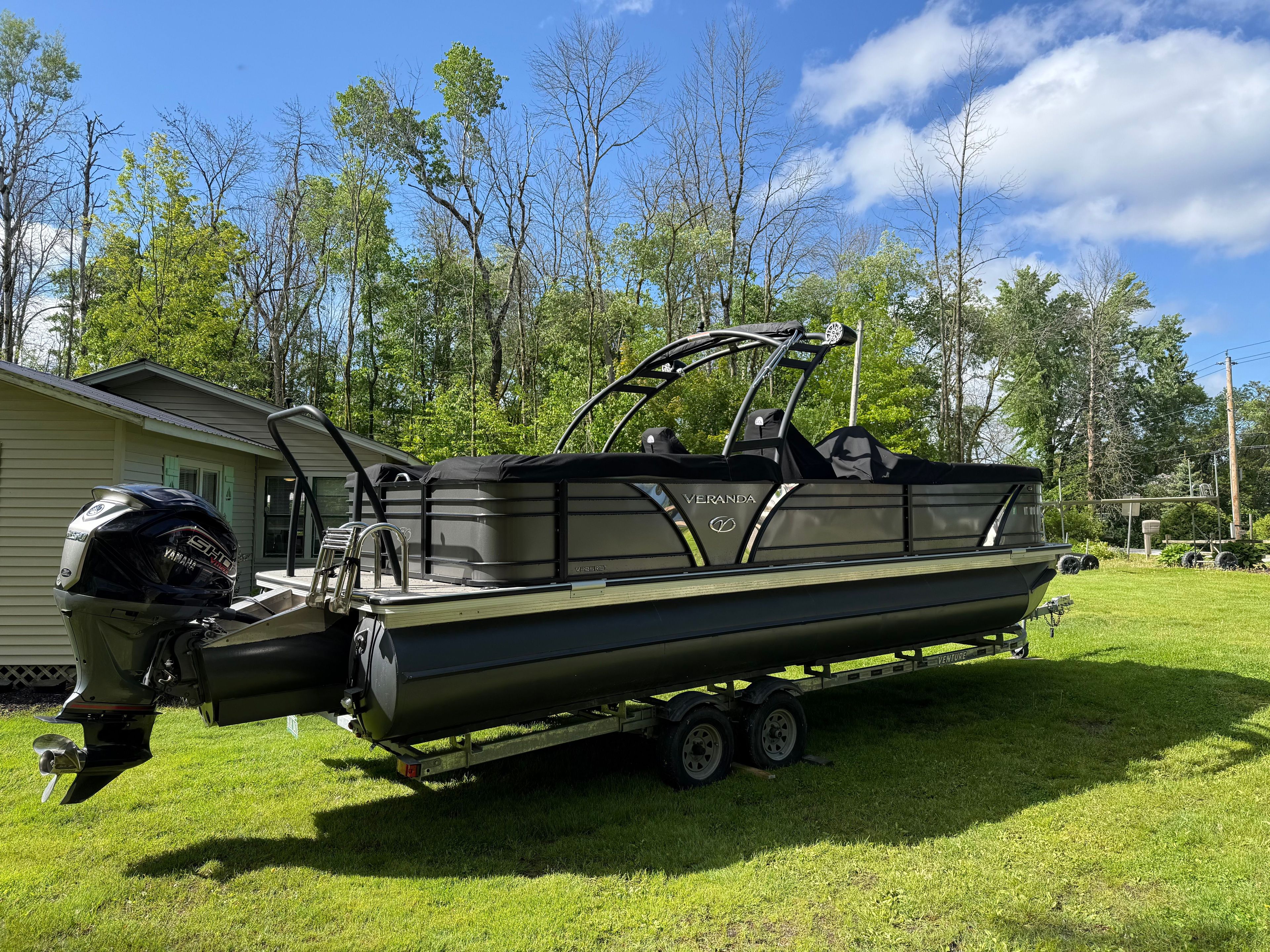 A 2024 Veranda VP 25RCT pontoon boat on a trailer on a grassy lawn.