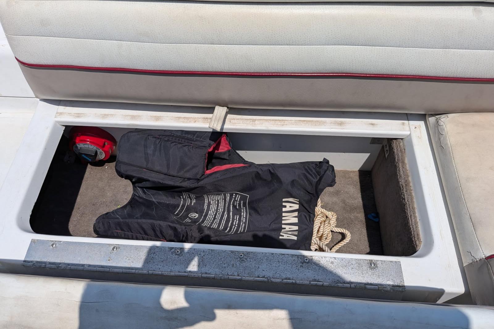 Storage compartment in a 2020 Cobalt 206 boat with life jacket and rope.