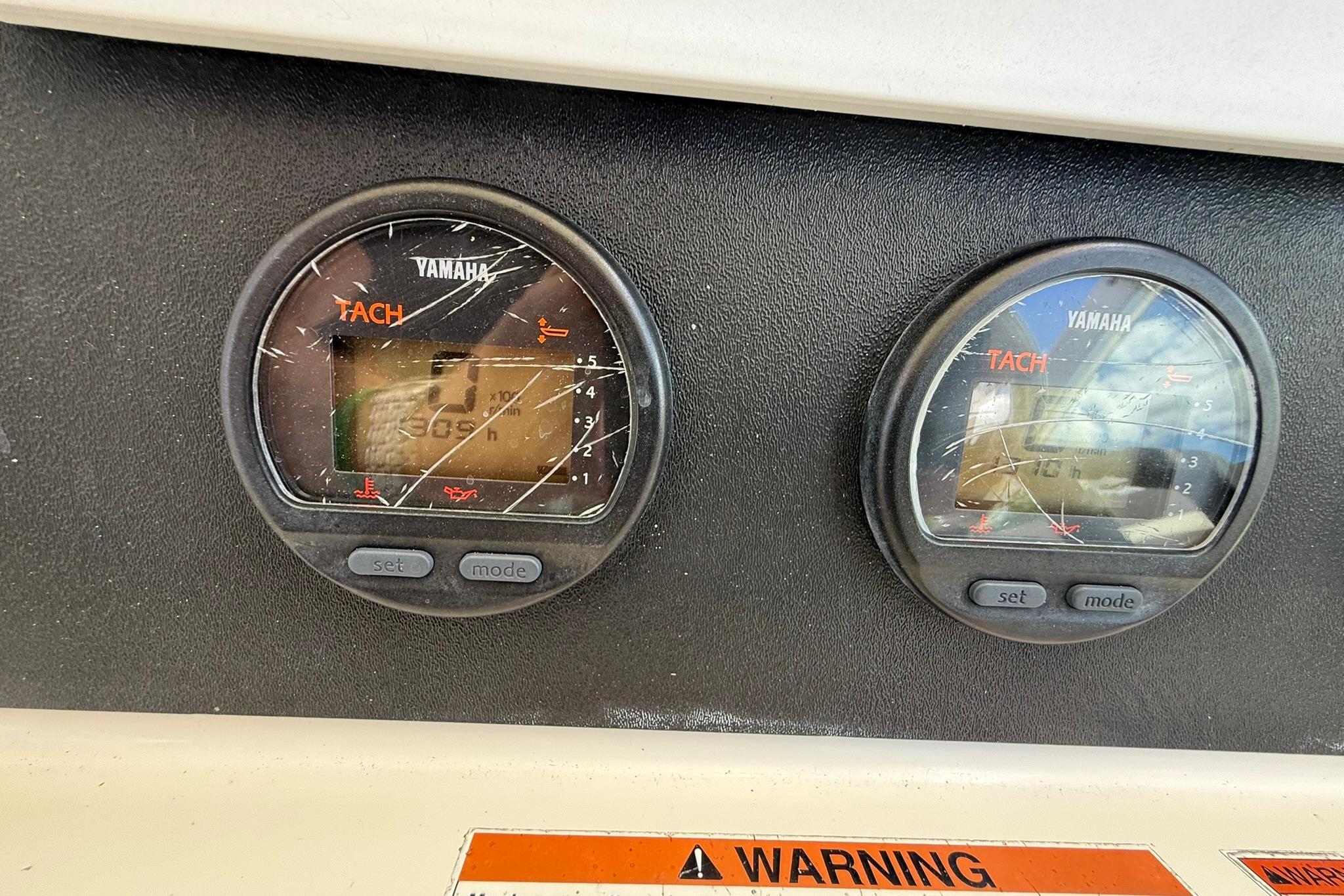 Yamaha tachometers on a 2003 Pursuit 2870 Walkaround boat dashboard with warning label.
