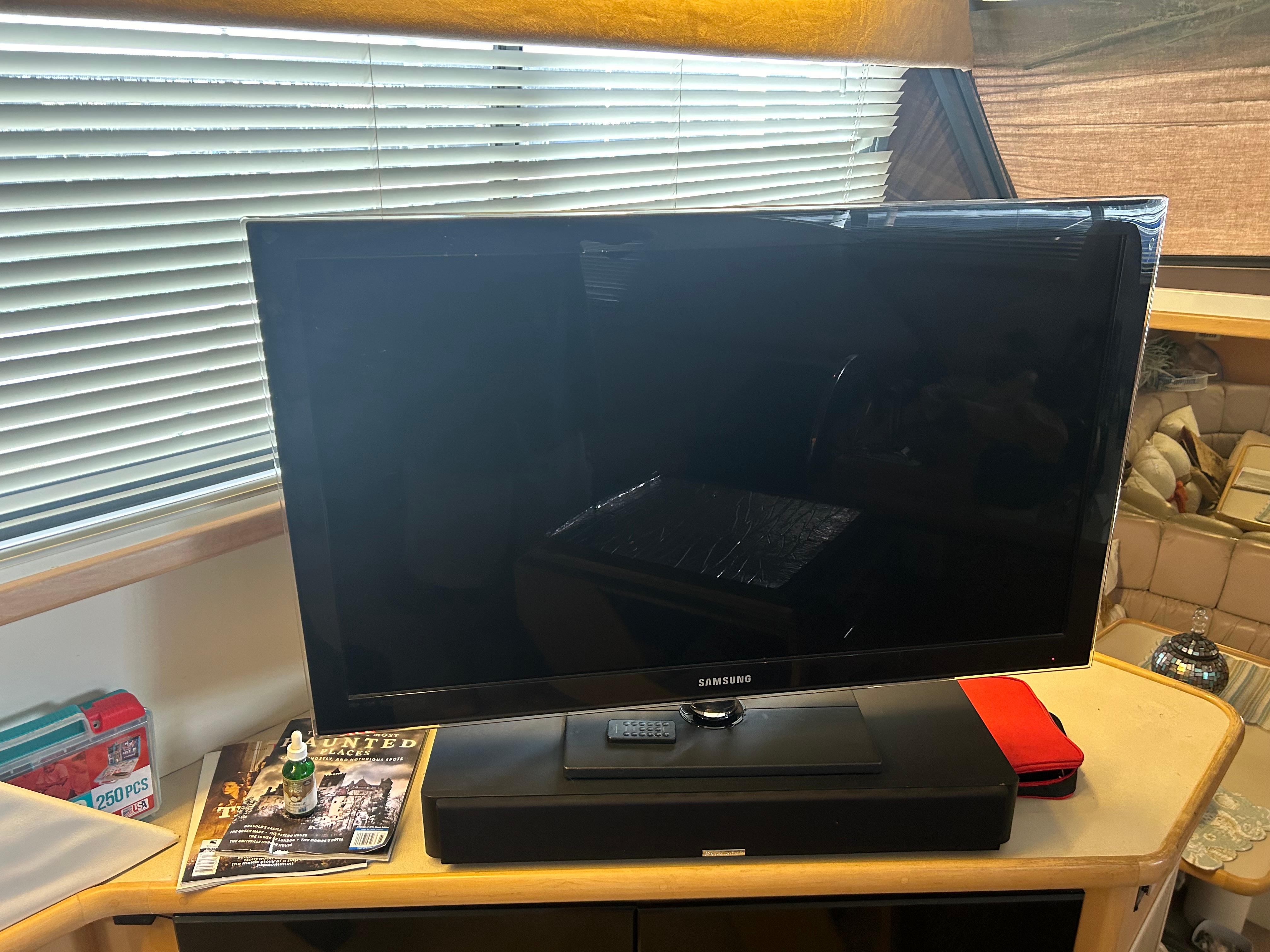 Television setup inside 1996 Carver 440 Aft Cabin Motor Yacht with magazines and decor.