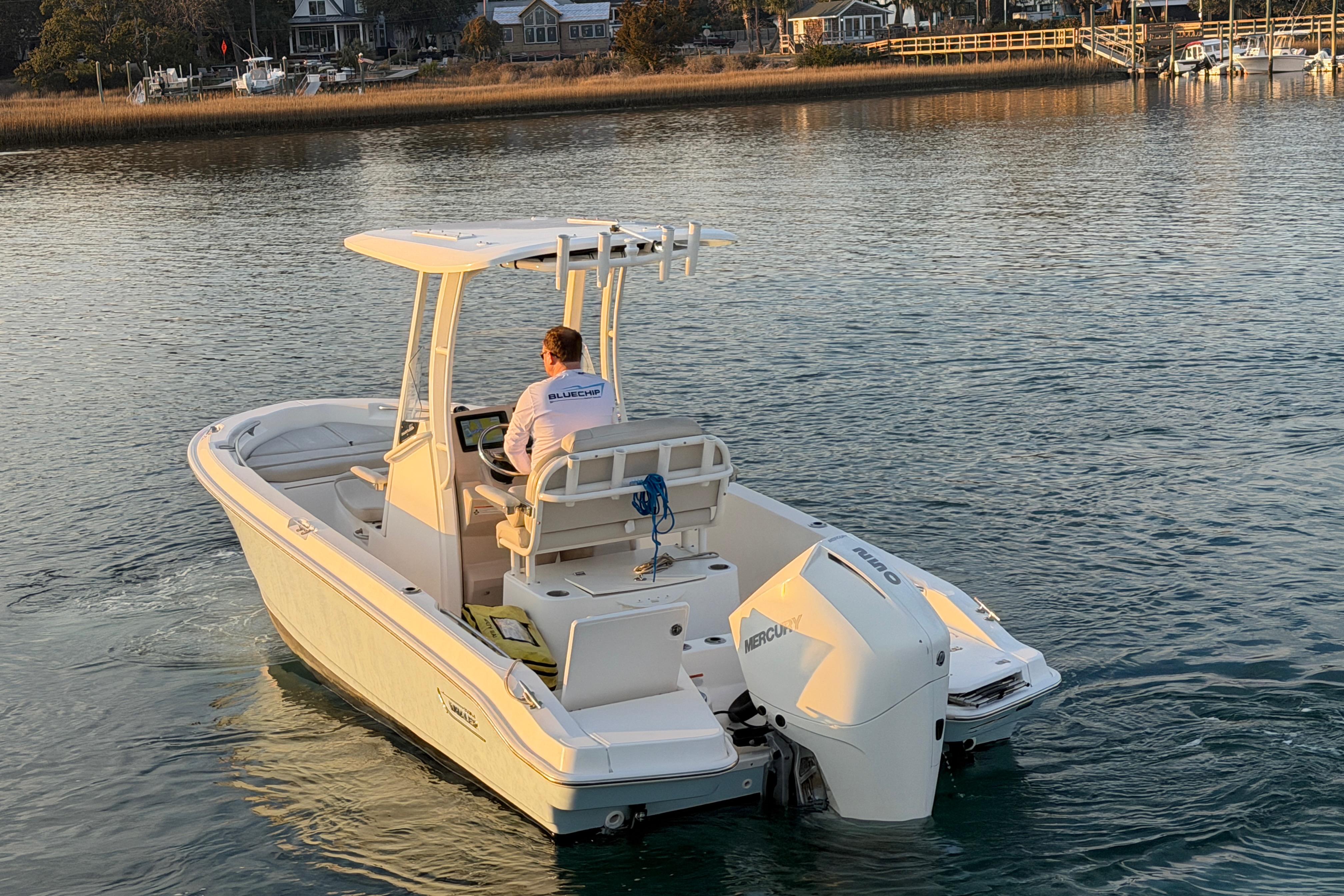 2023 Boston Whaler 220 Dauntless boat cruising on calm water near a shoreline.