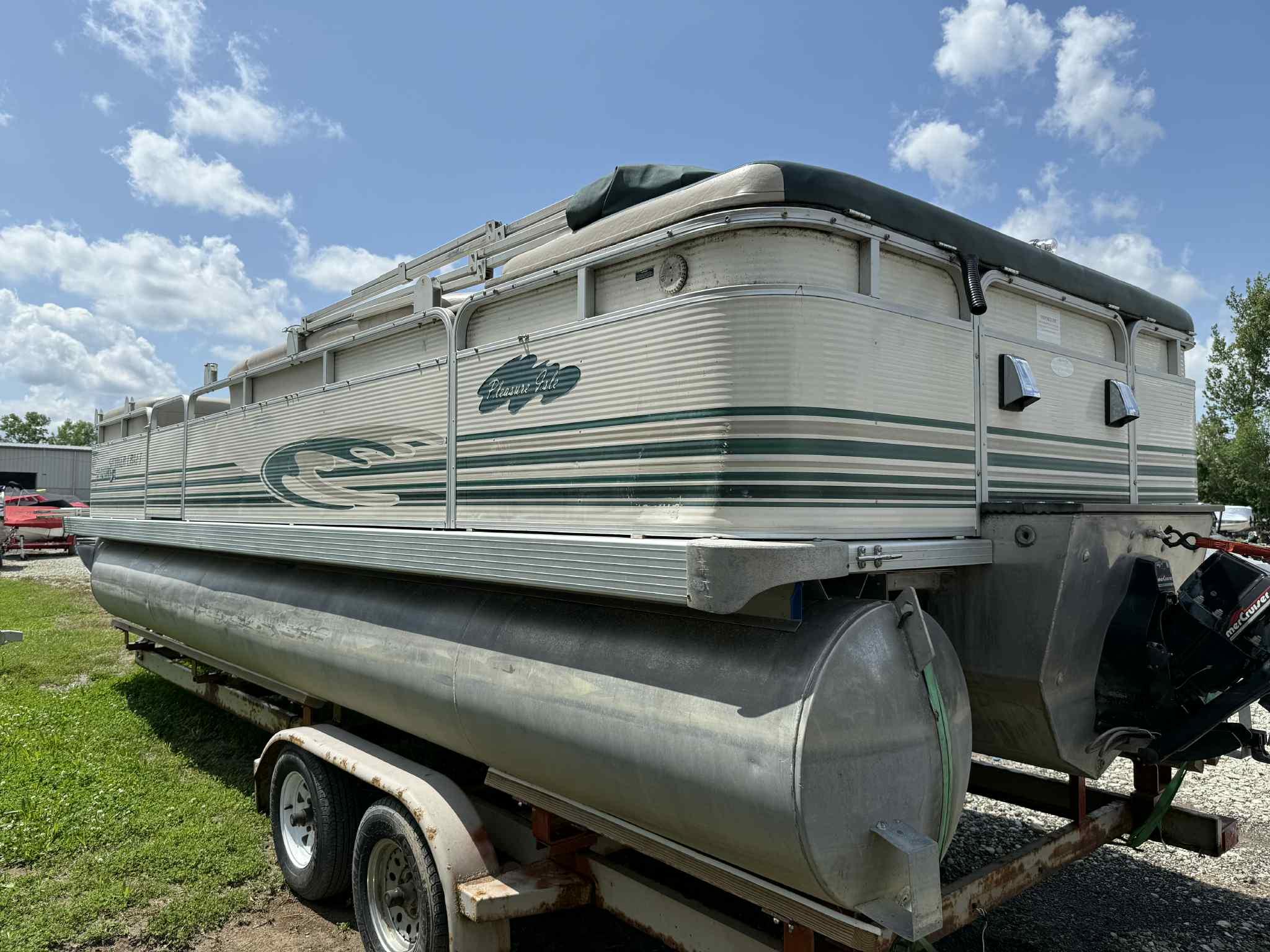 1999 Smoker Craft 8526 Pleasure Isle I/O pontoon boat on trailer under blue sky.