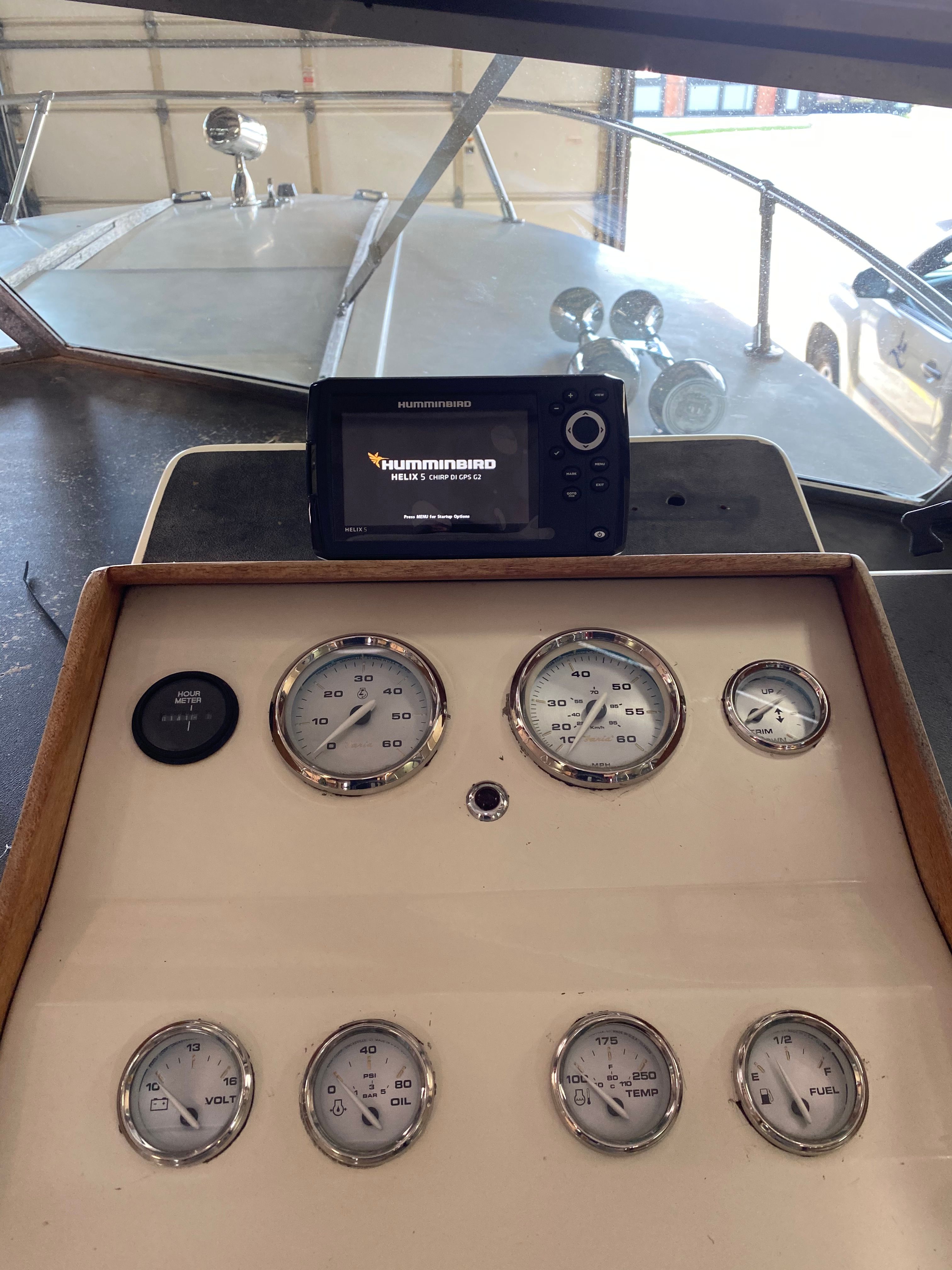 Dashboard of a 1976 Formula 233 with various gauges and a Humminbird device.