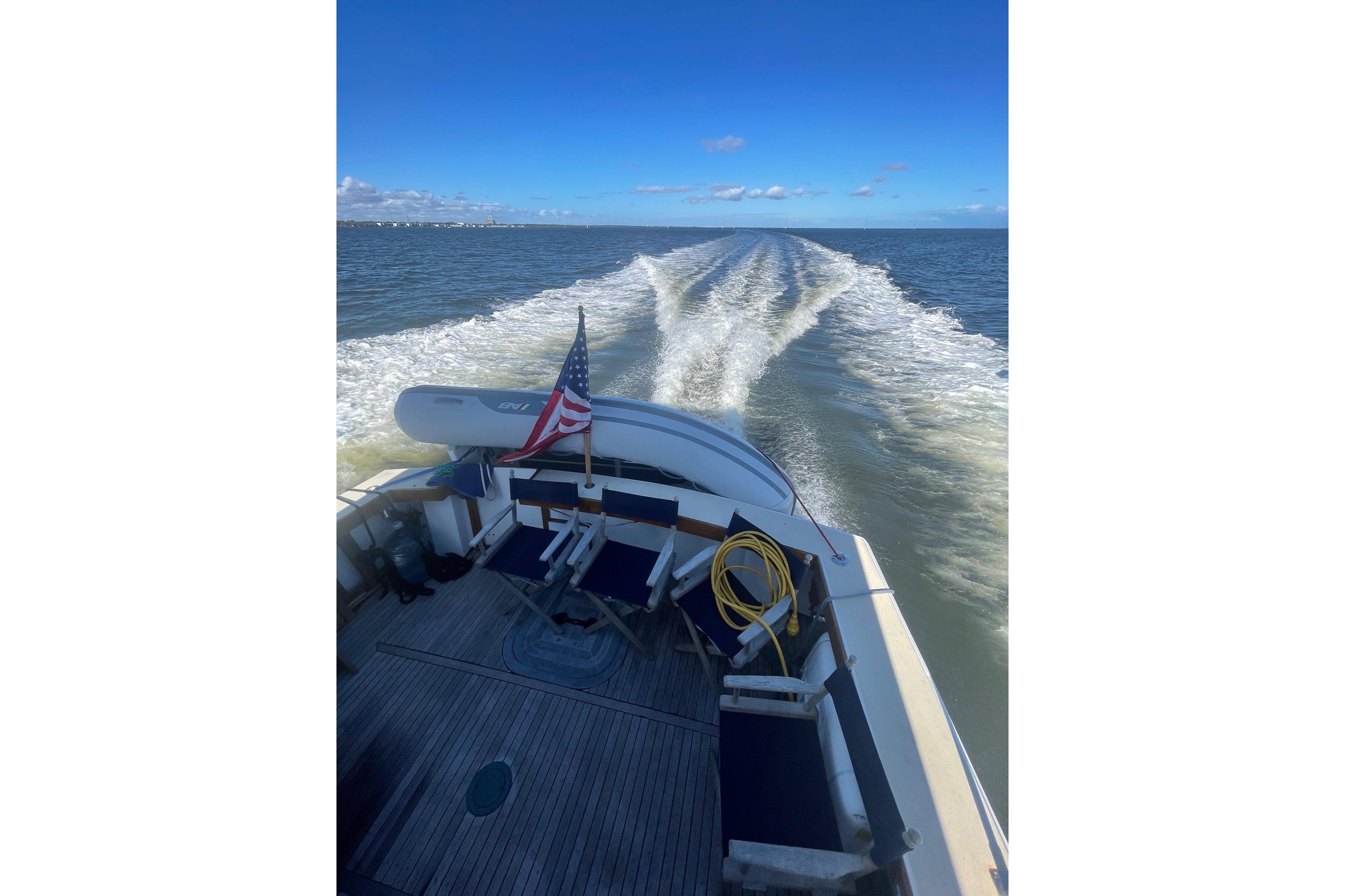 A 1987 Lyman-Morse Hunt 42 boat cruising on open water under a clear blue sky.
