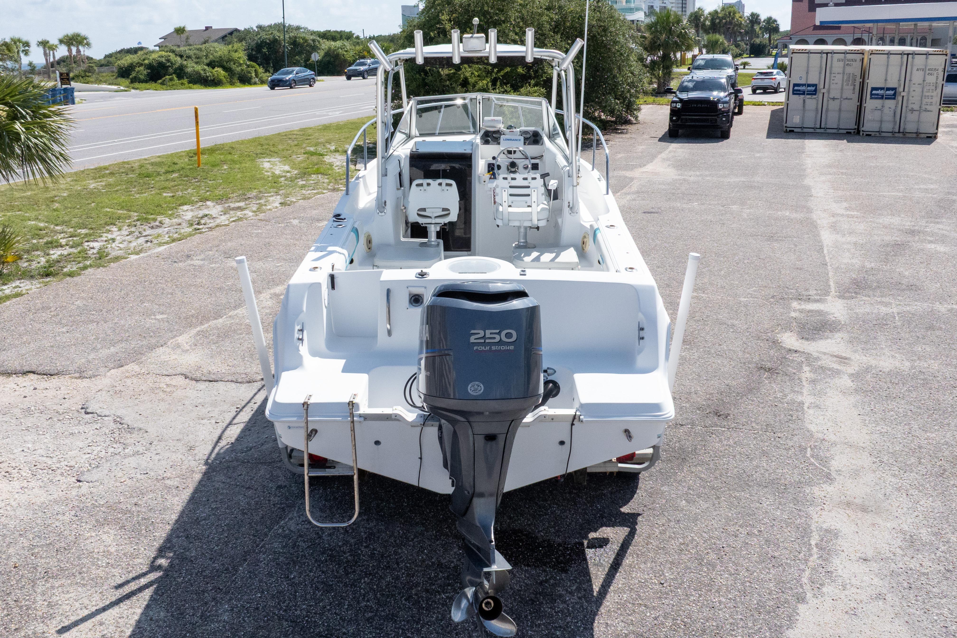 1999 Aquasport 225 Explorer boat with Yamaha 250 outboard motor, parked on a sunny day.