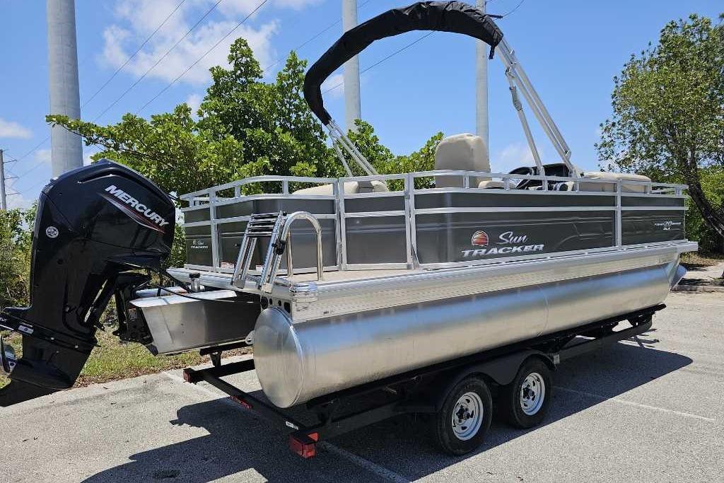 2025 Sun Tracker SportFish 20 DLX pontoon boat on trailer, featuring Mercury outboard motor.