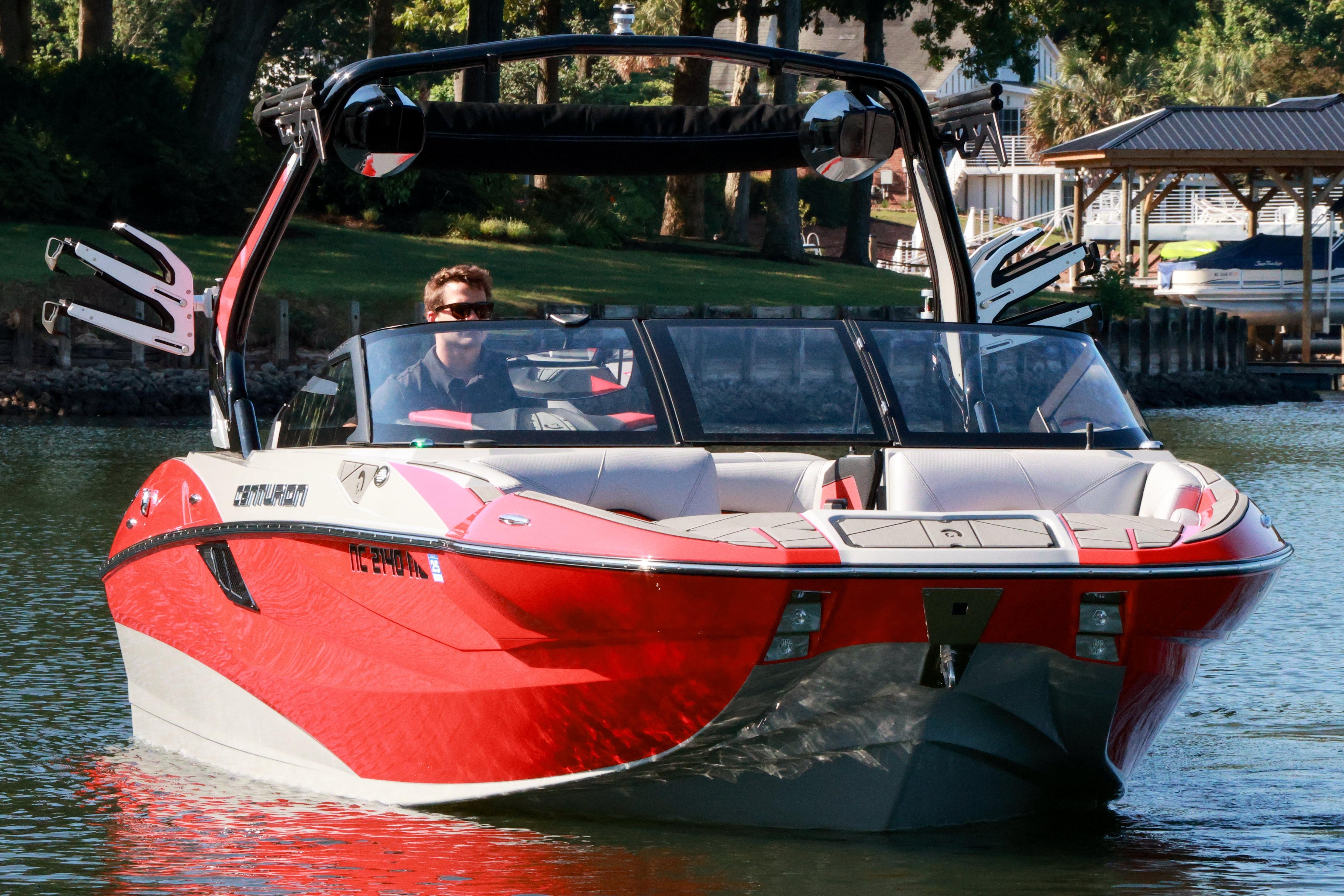2024 Centurion Fi23 boat in vibrant red on a serene lake.