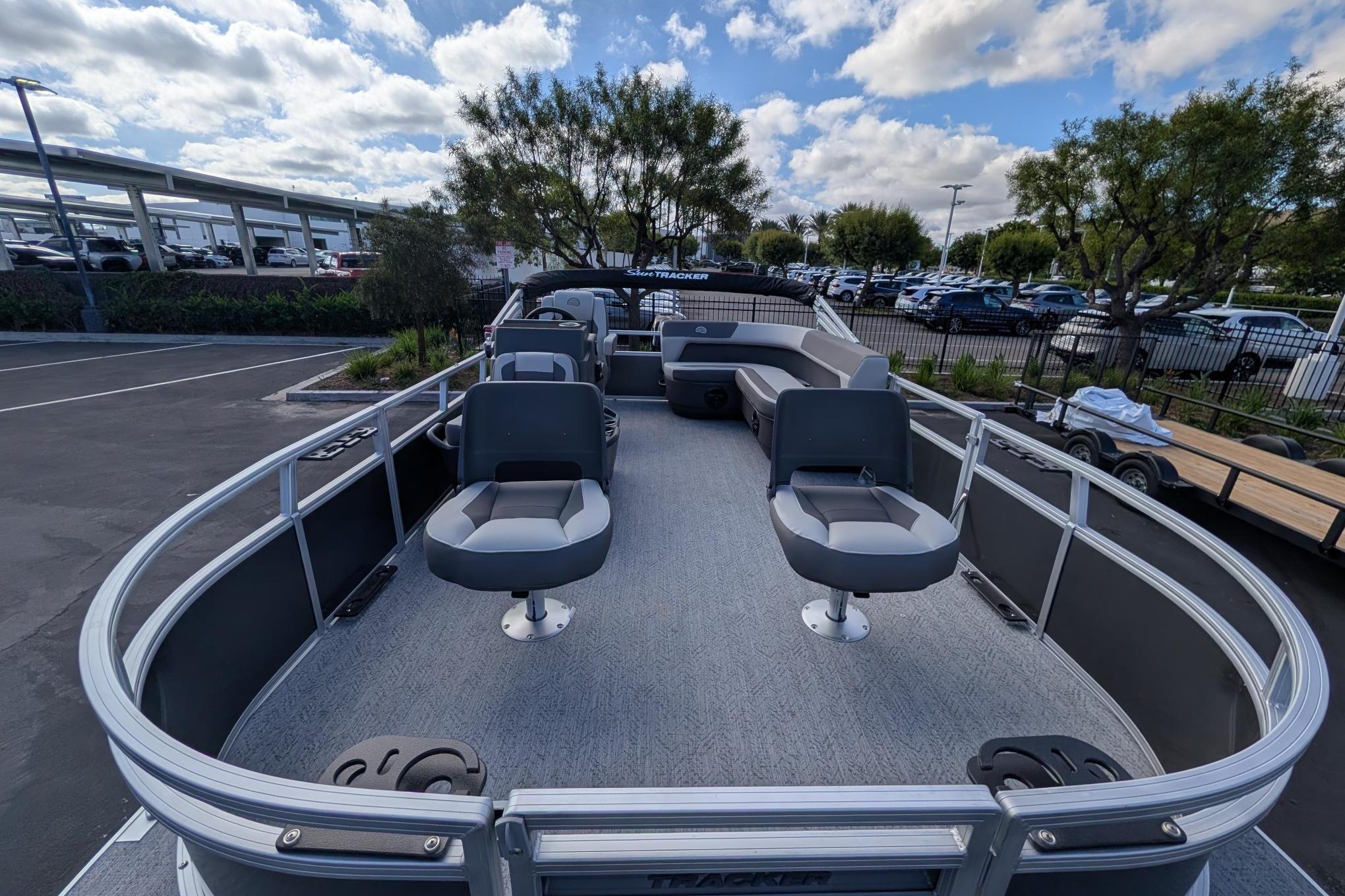 2026 Sun Tracker Bass Buggy 16 XL Select pontoon boat with seating, parked outdoors.