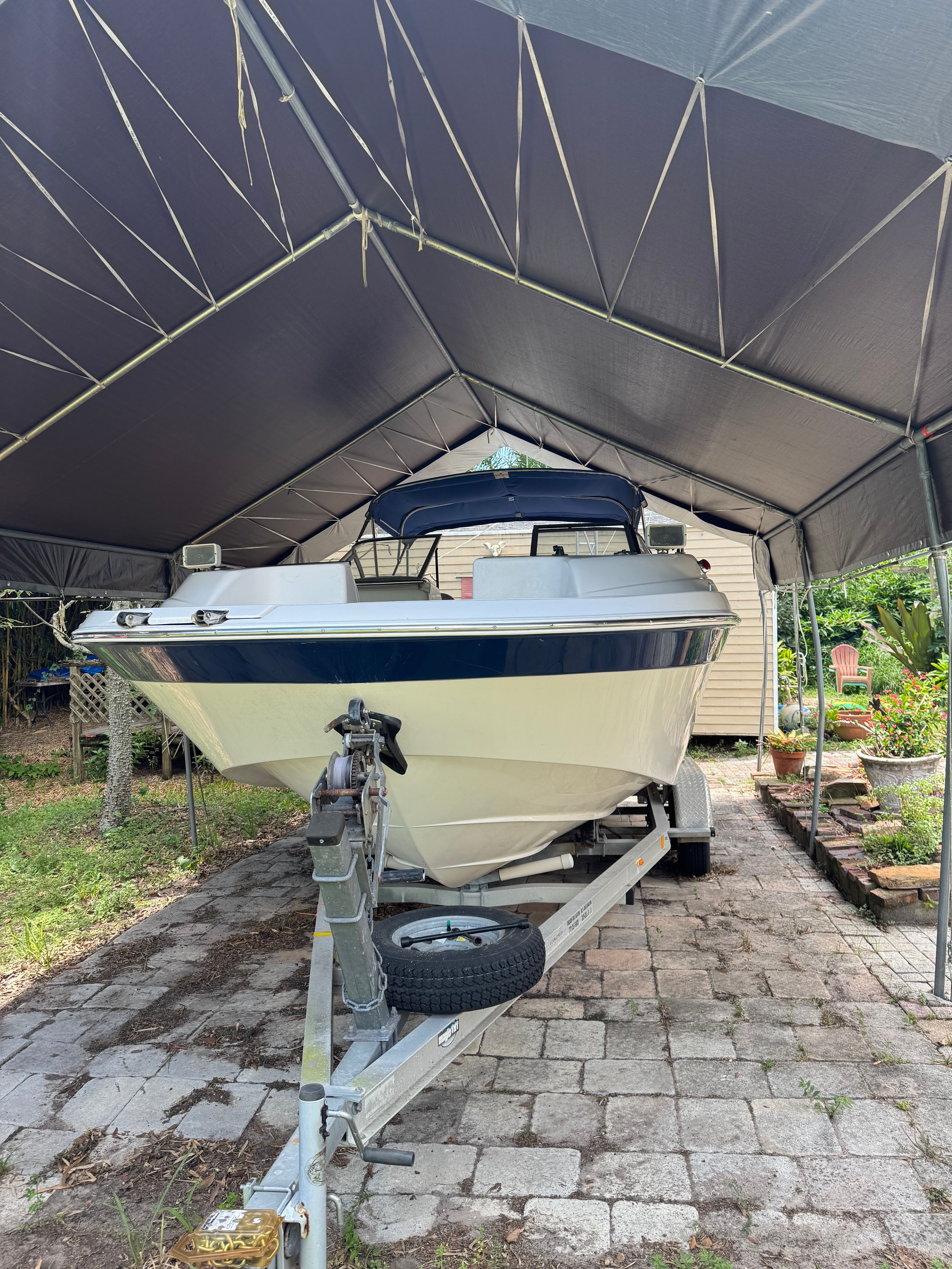 A 2004 Custom DB212 boat on a trailer under a covered area.