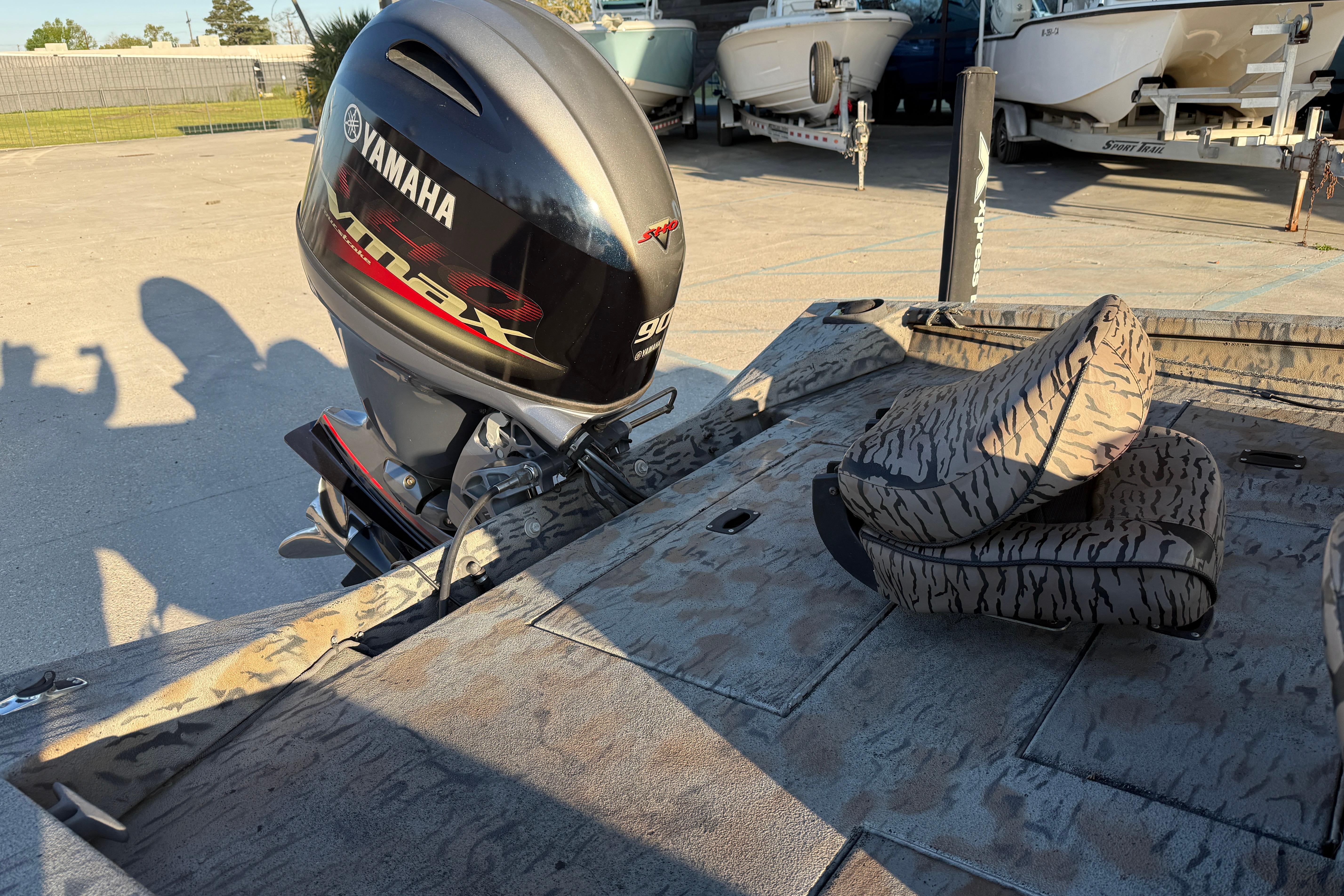 2019 Xpress XP7 boat with Yamaha Vmax engine, camo seats, and parked boats in background.