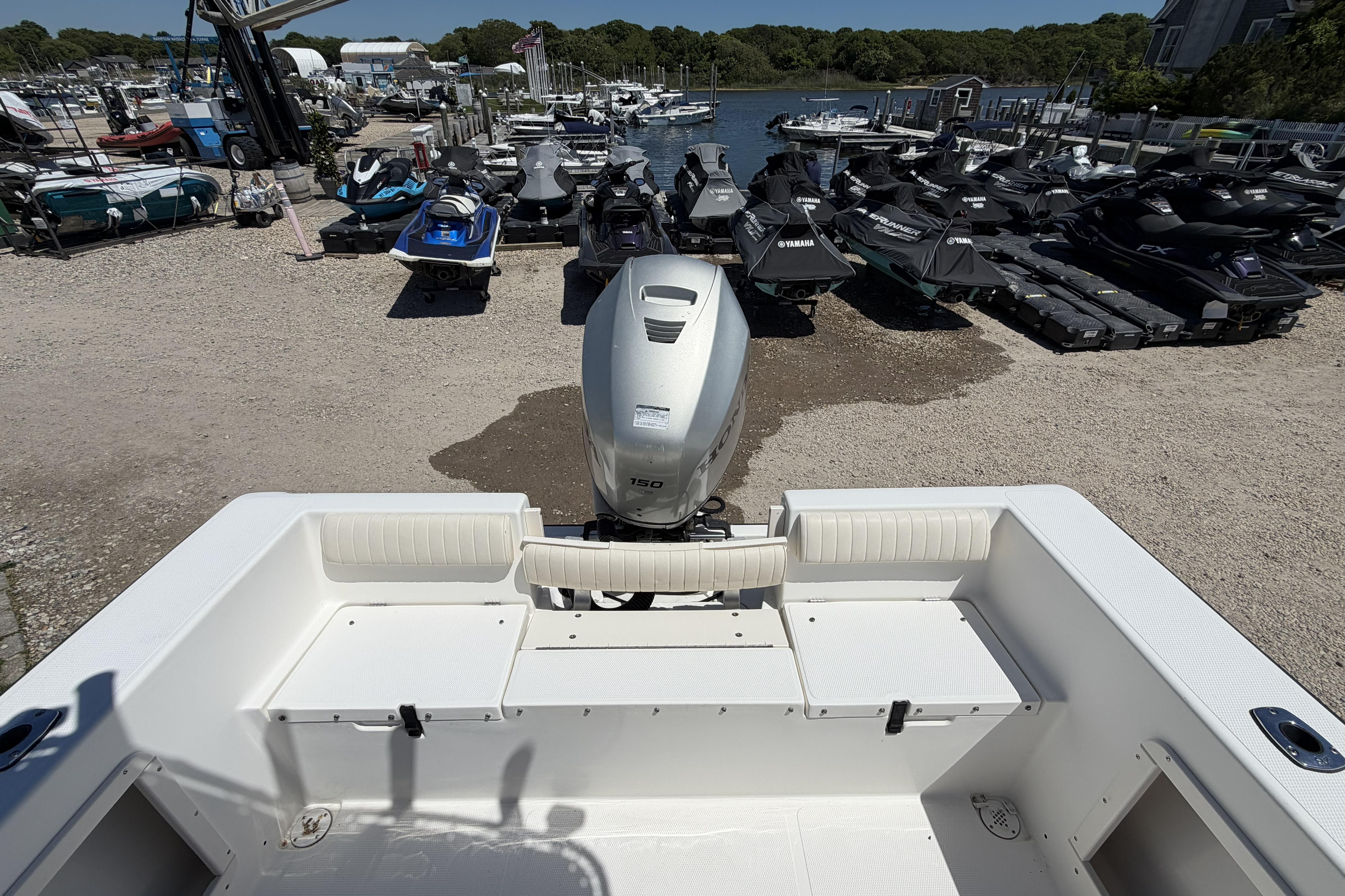 2006 Mako 212 Center Console boat with outboard motor, docked near jet skis.