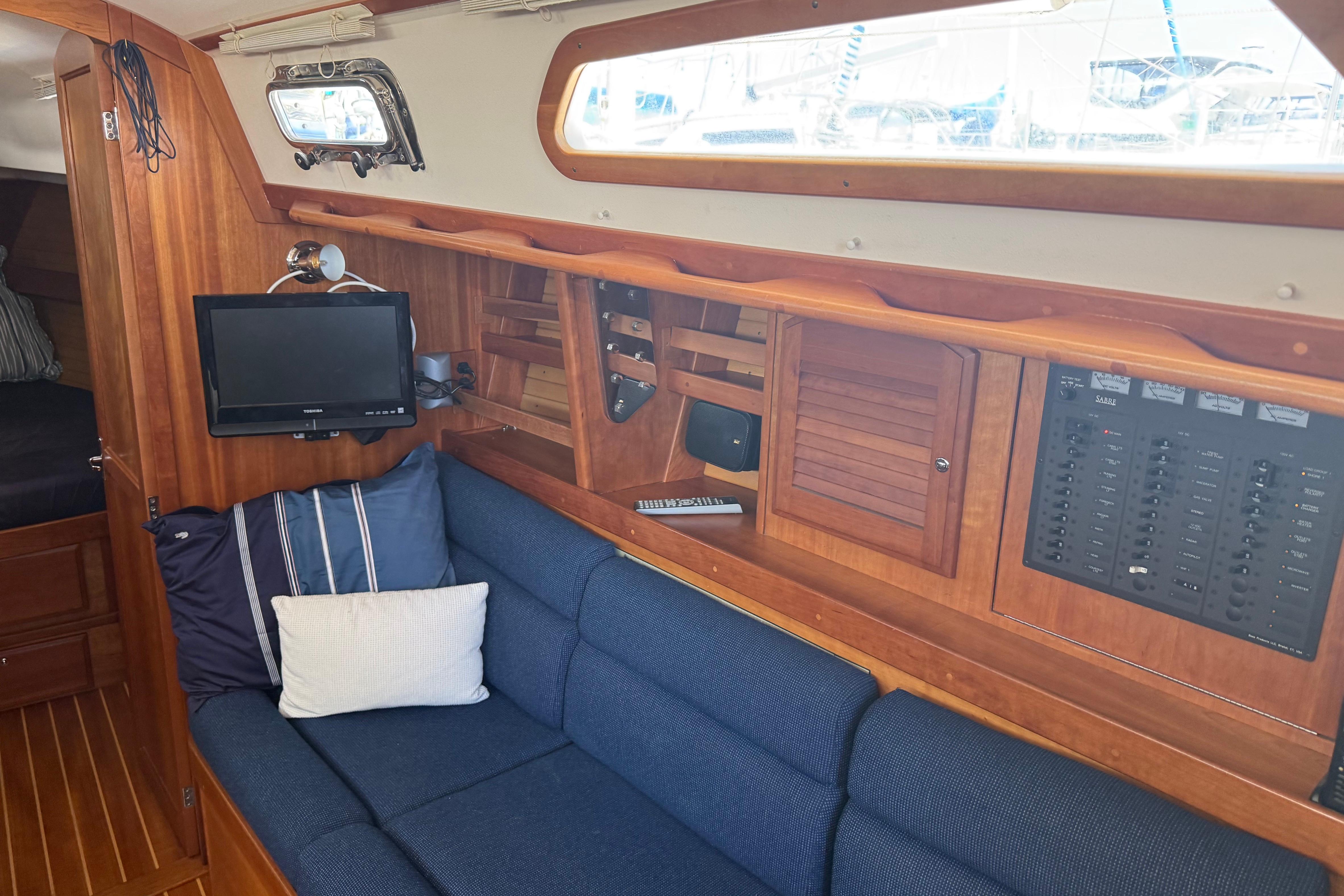 Interior of 2004 Sabre 386 sailboat with blue sofa, TV, and wooden cabinetry.