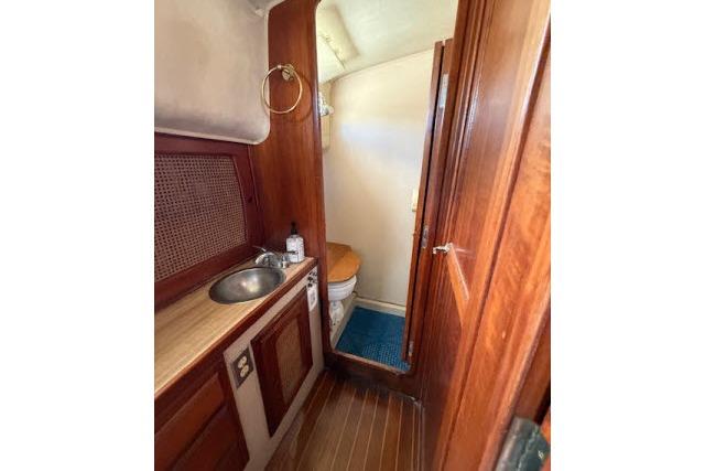 1982 Lancer 45 Motorsailer bathroom with wooden cabinetry, sink, and toilet.