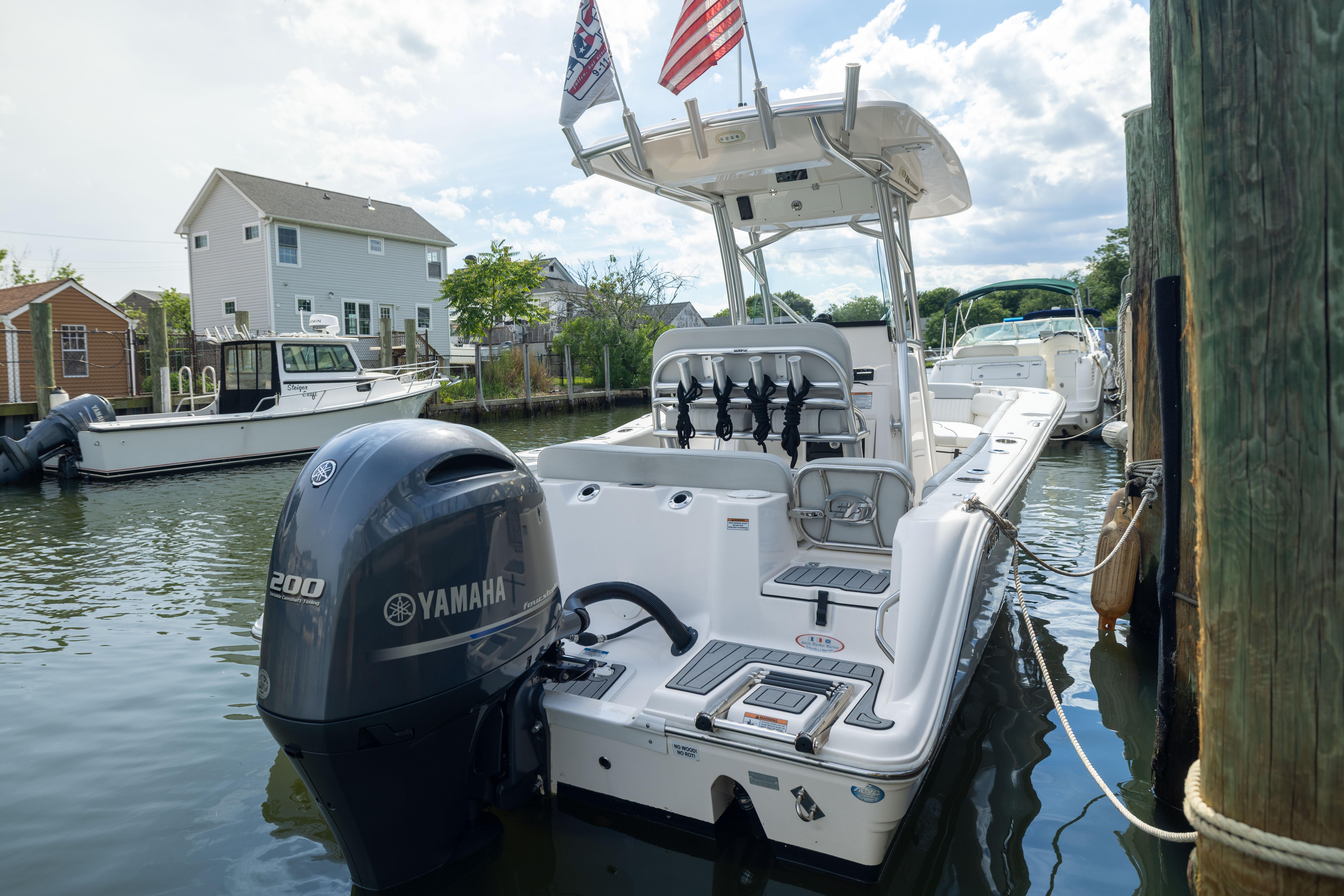 2023 Sea Fox 228 Commander boat docked, featuring Yamaha 200 engine, flags, and residential backdrop.