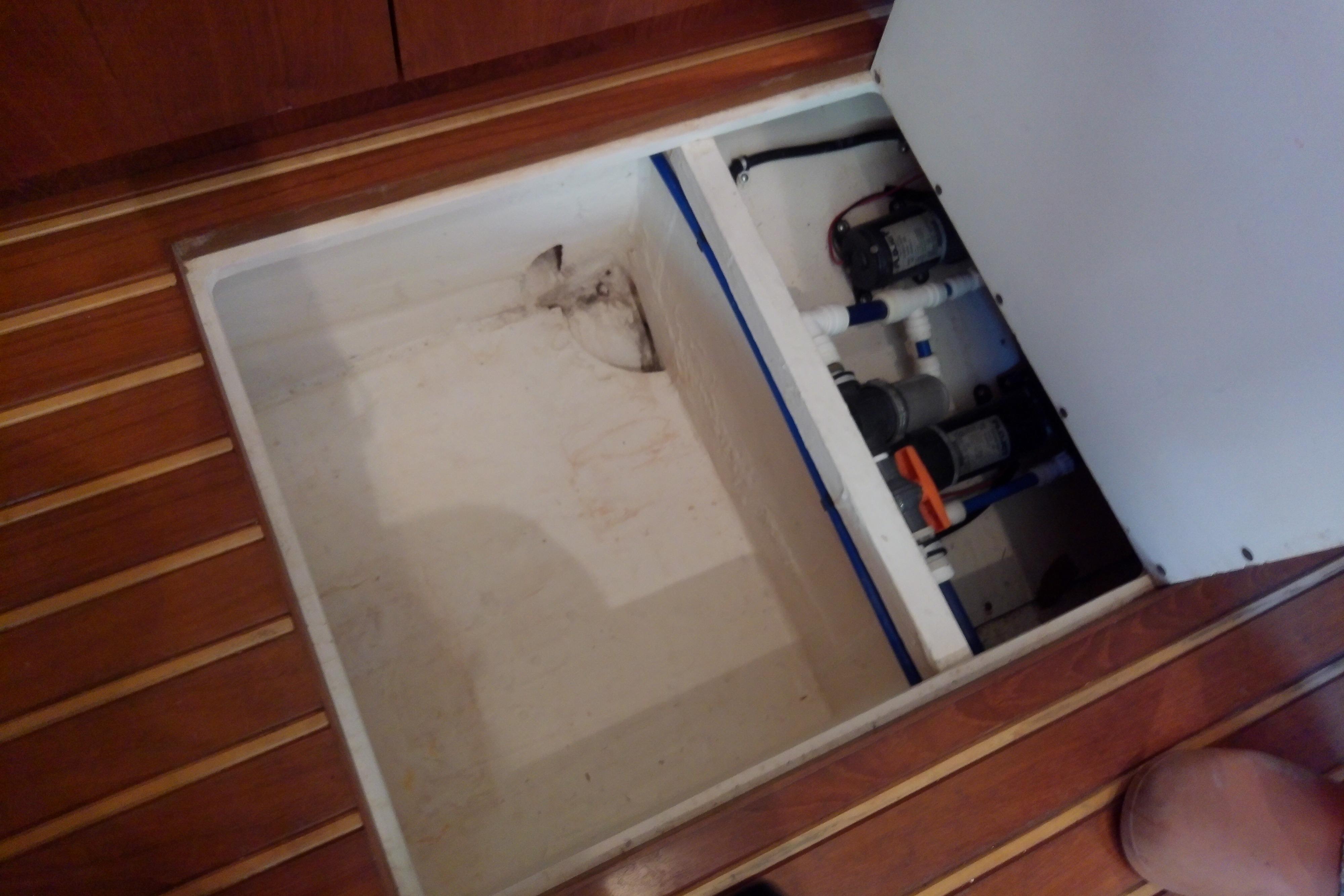 Bilge compartment of 2000 Tiara Yachts 4100 Open, showcasing pumps and wooden flooring.