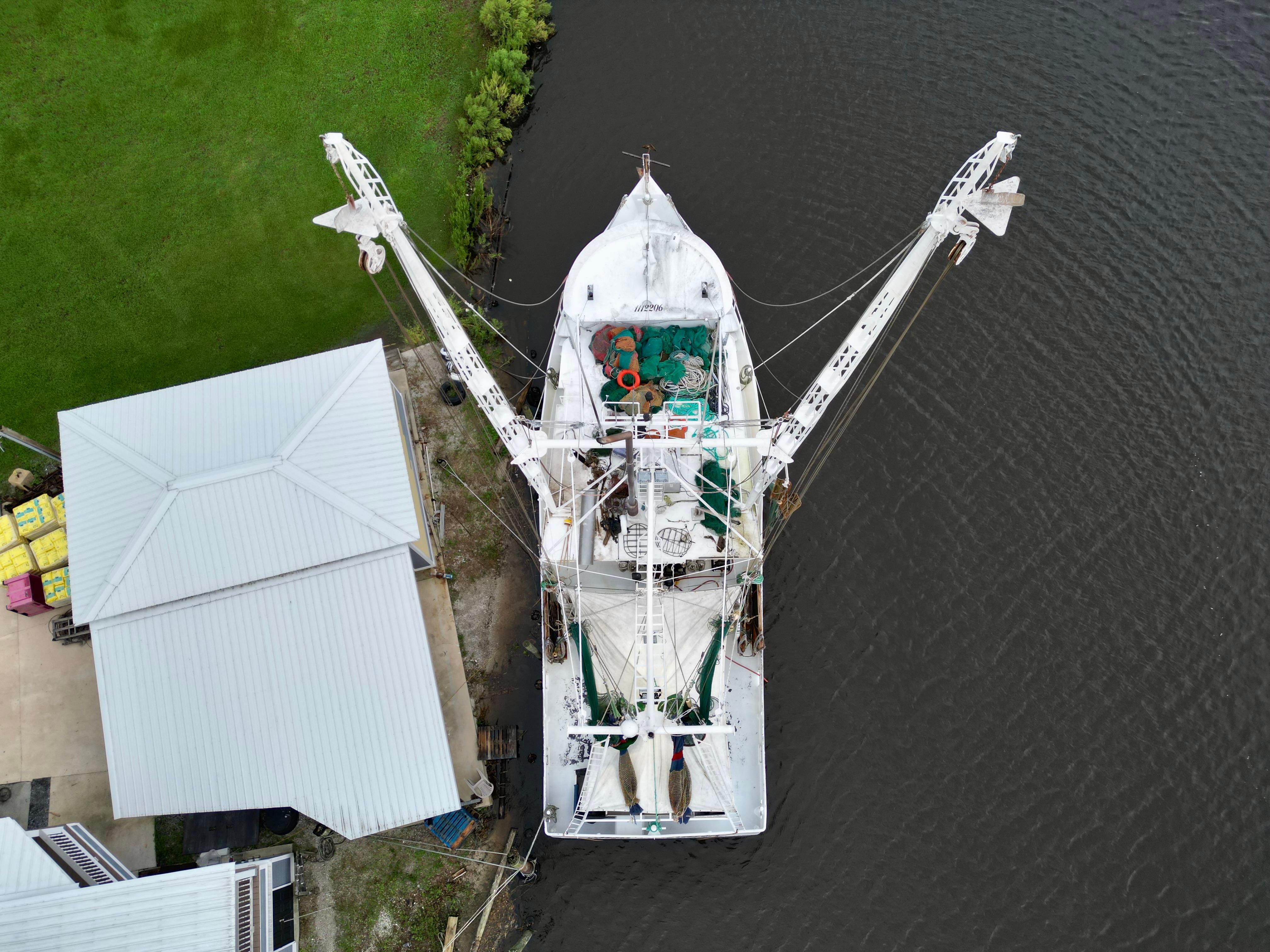 Aerial view of 2001 Blanchard 69 Shrimper/Freezer docked by a riverside building.