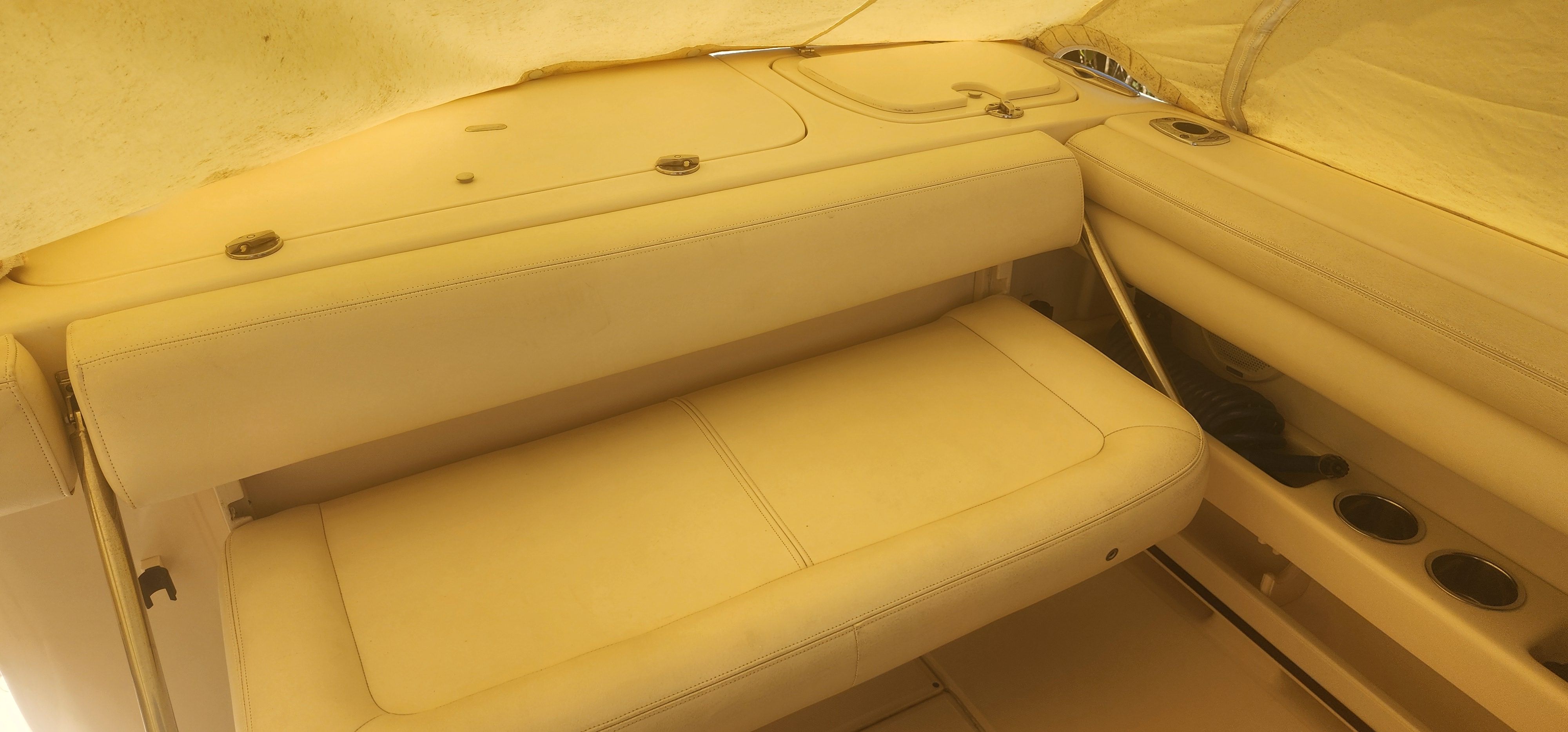 The image shows a beige bench seat inside a boat, surrounded by covers.