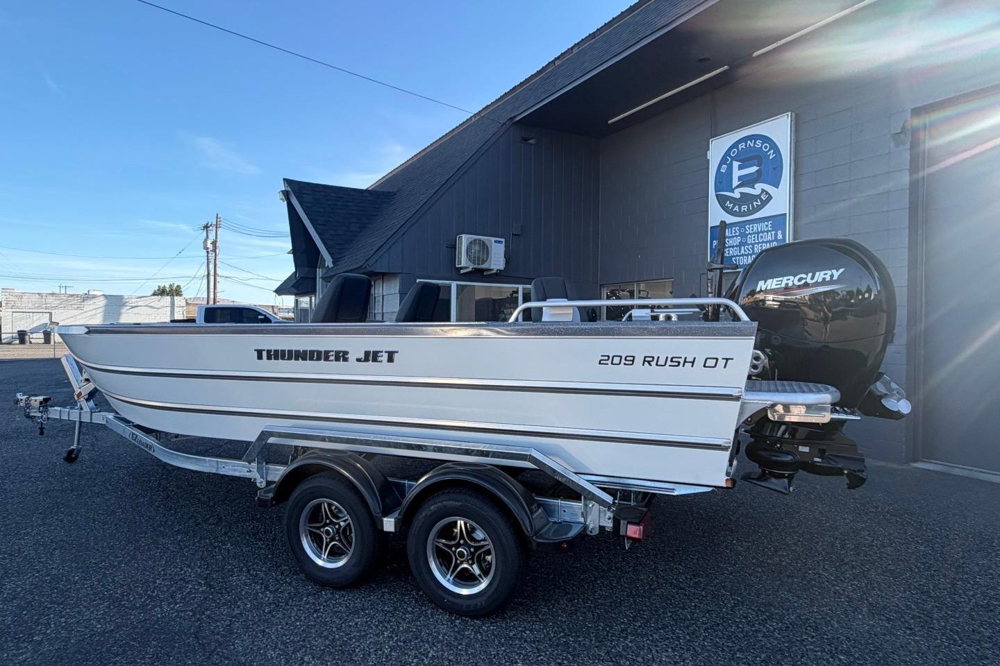 2026 Thunder Jet 209 Rush OT boat with Mercury engine, parked outside marine shop.
