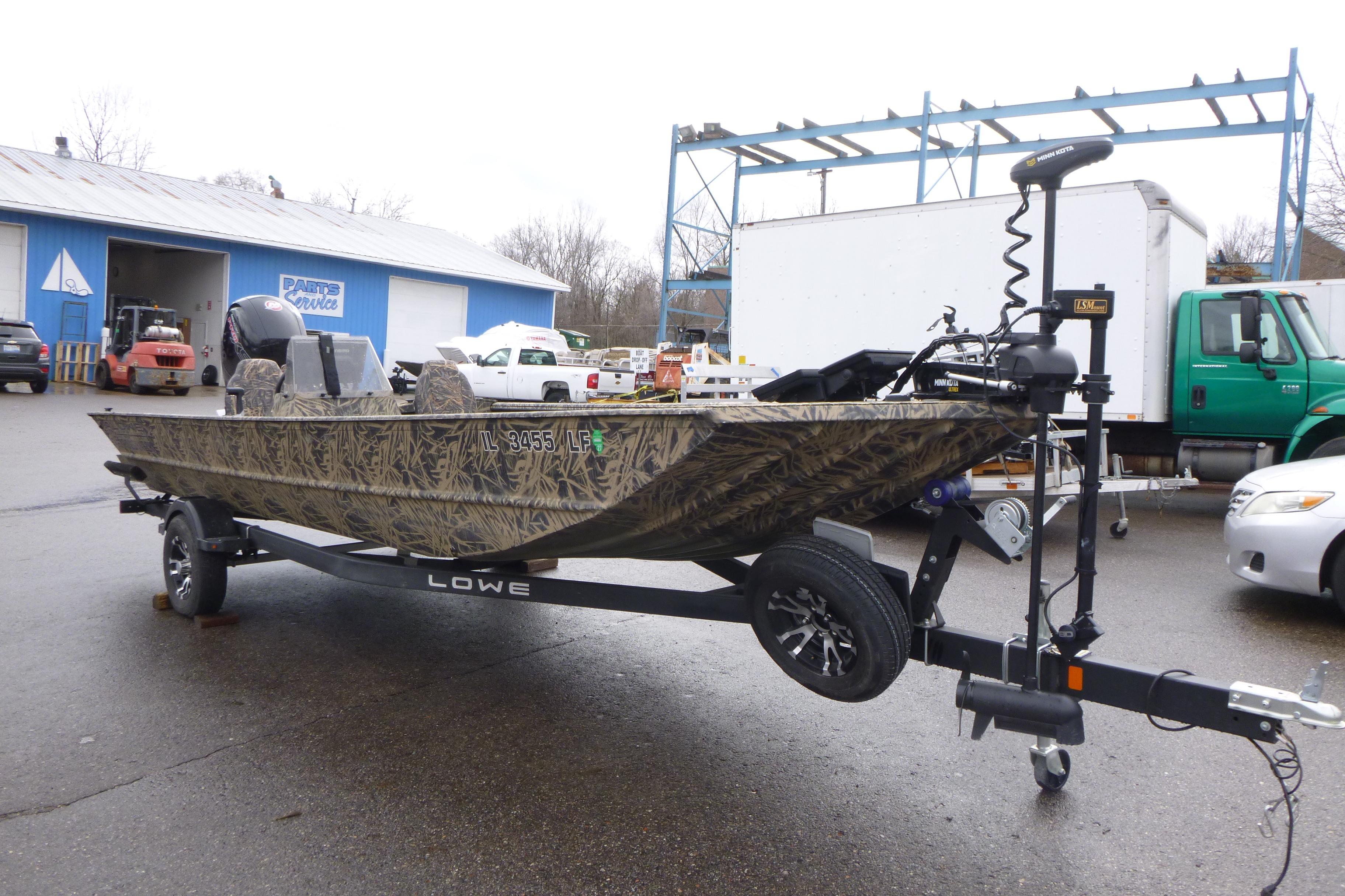 2024 Lowe Roughneck 2070 boat on trailer, camo design, parked outdoors.