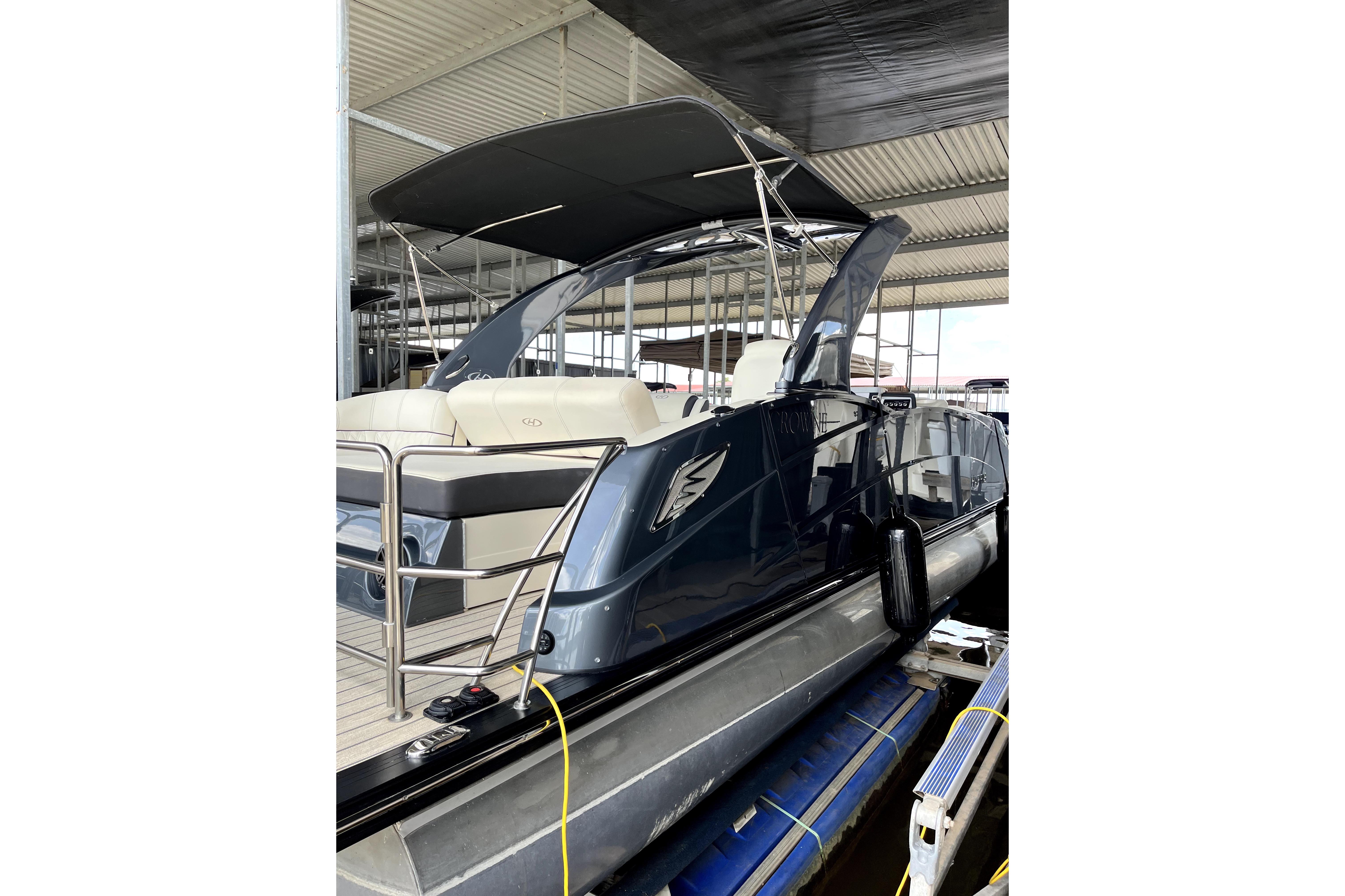 2021 Harris Crowne SL 250 pontoon boat docked under a covered marina.