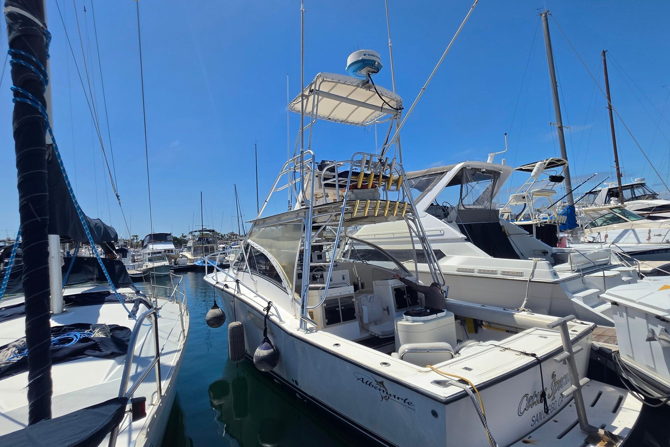 1999 Albemarle 305 Express Fisherman boat docked in a marina under clear blue skies.