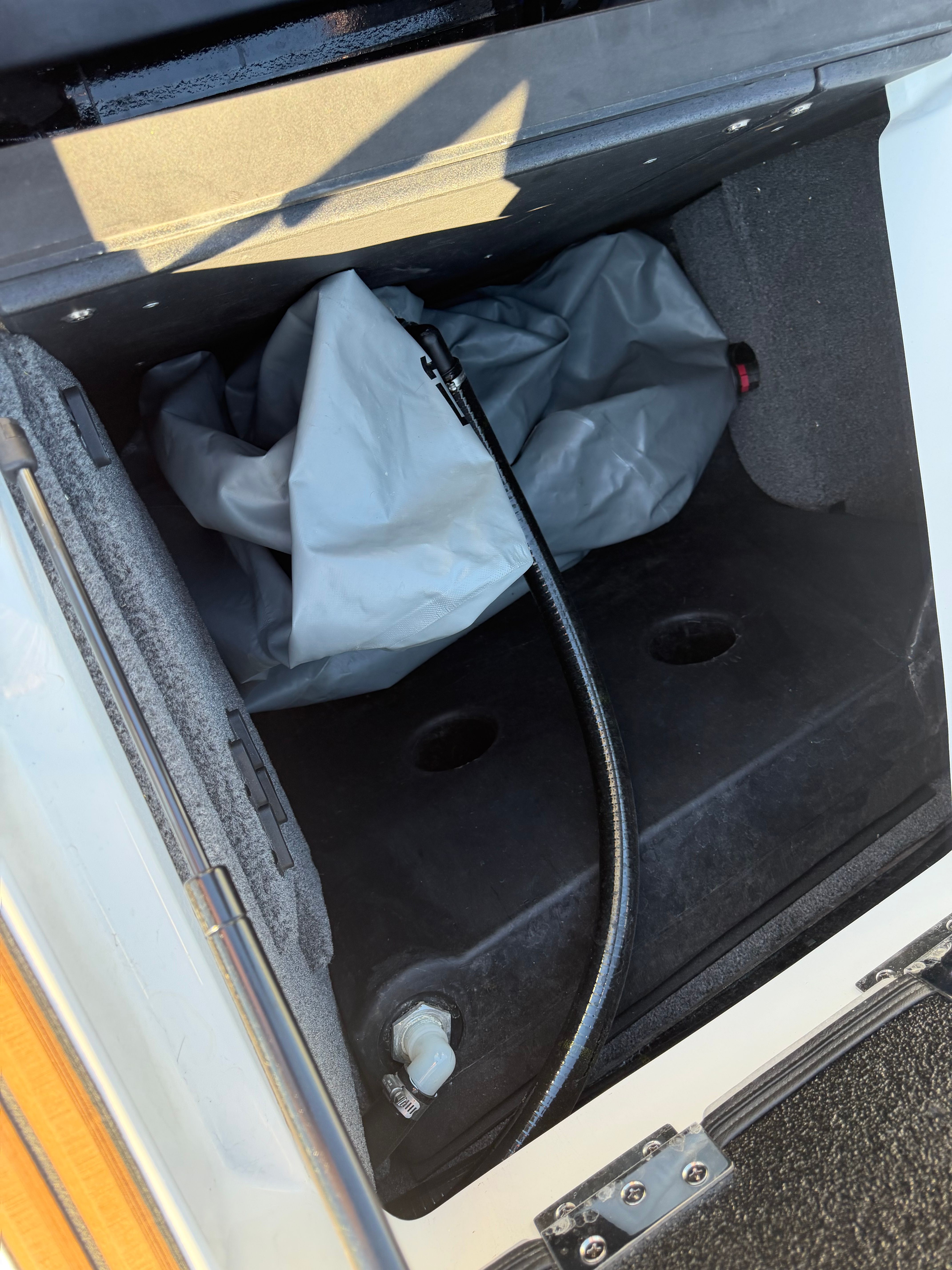 A storage compartment in the boat with a hose and cover.