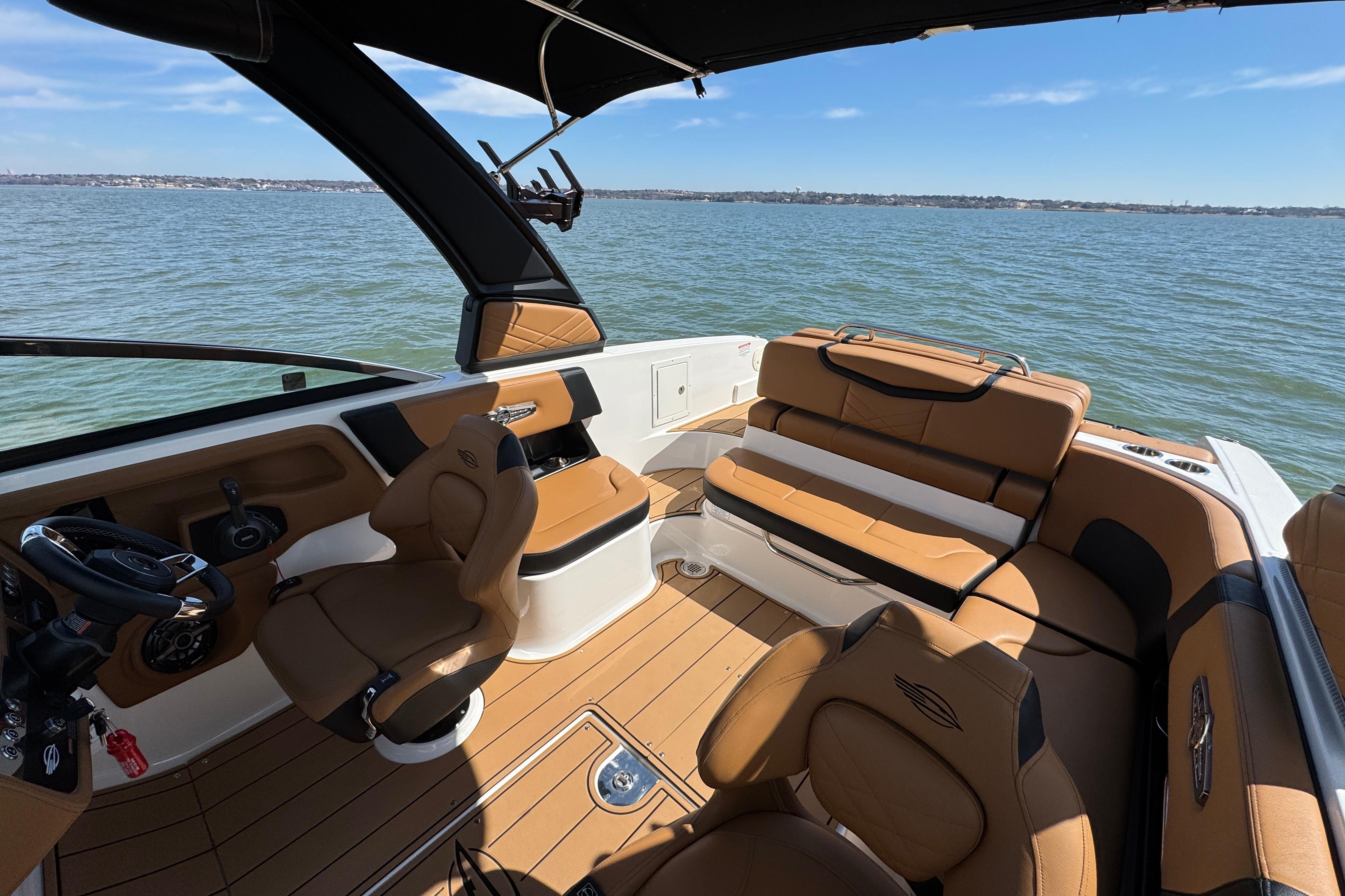 2023 Chaparral 26 Surf boat interior with tan seating on a sunny day.