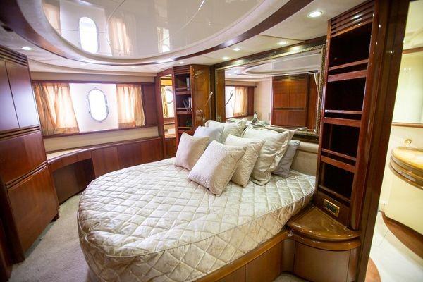 Luxurious bedroom interior of 2003 Azimut 74 Solar yacht with elegant wood finishes and plush bedding.