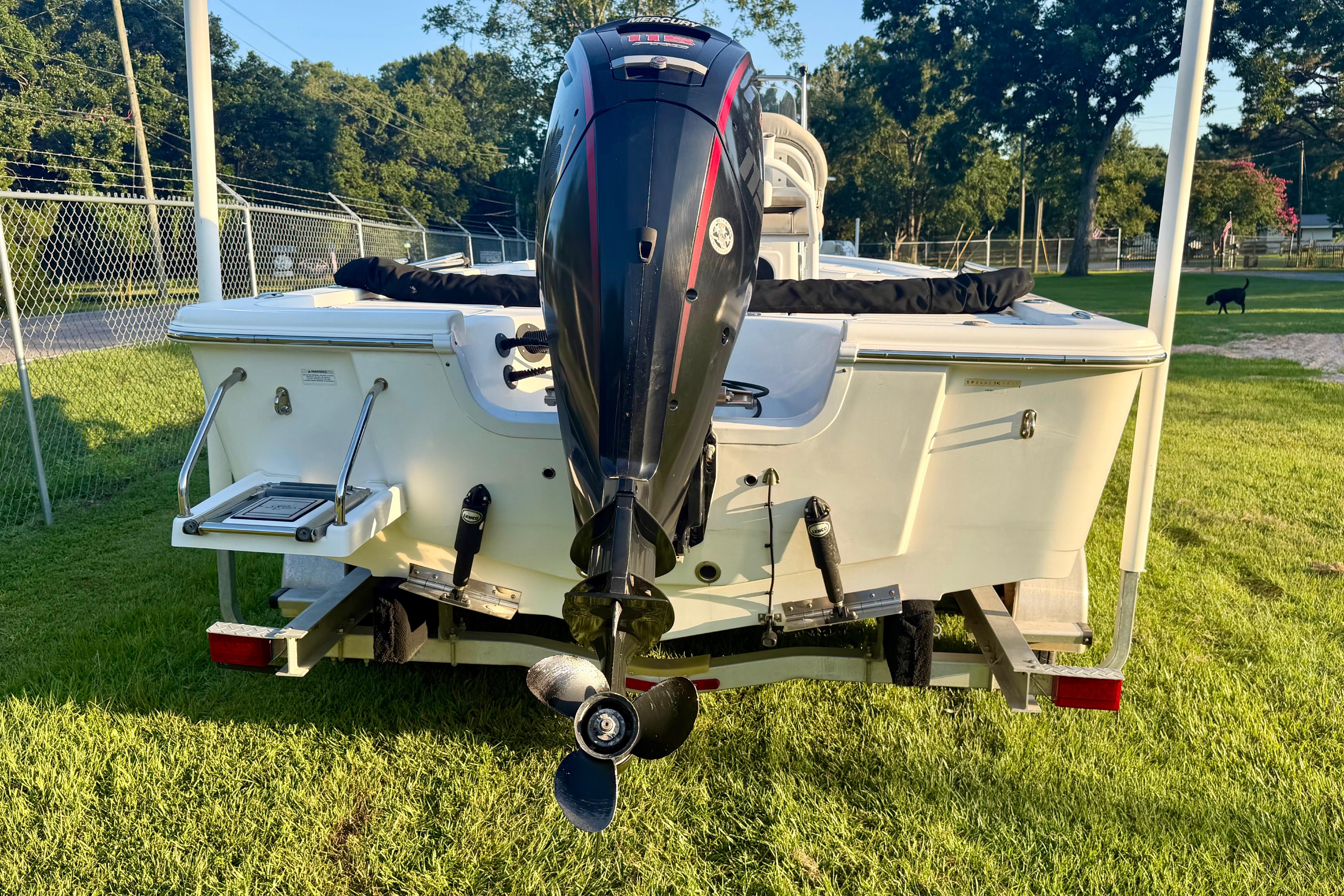 2018 Sea Pro 208 Bay boat with outboard motor on trailer, parked on grass.