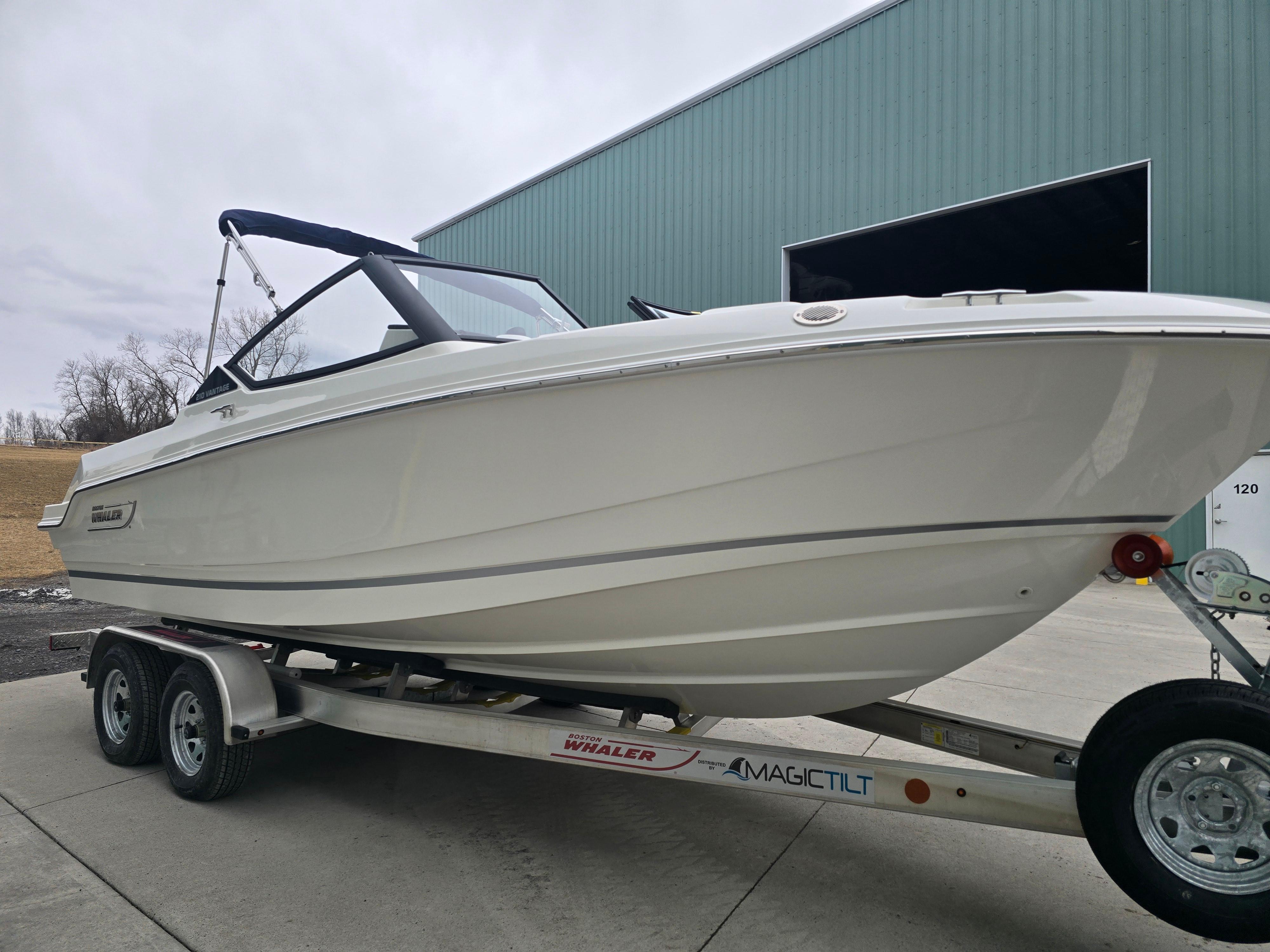 2025 Boston Whaler 210 Vantage boat on trailer near large building.
