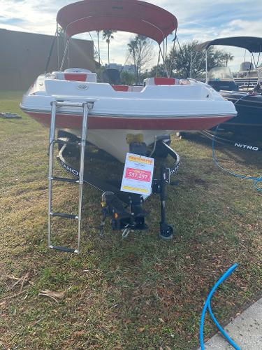 2022 Tahoe 2150 boat on display with price sign, ladder, and red canopy.