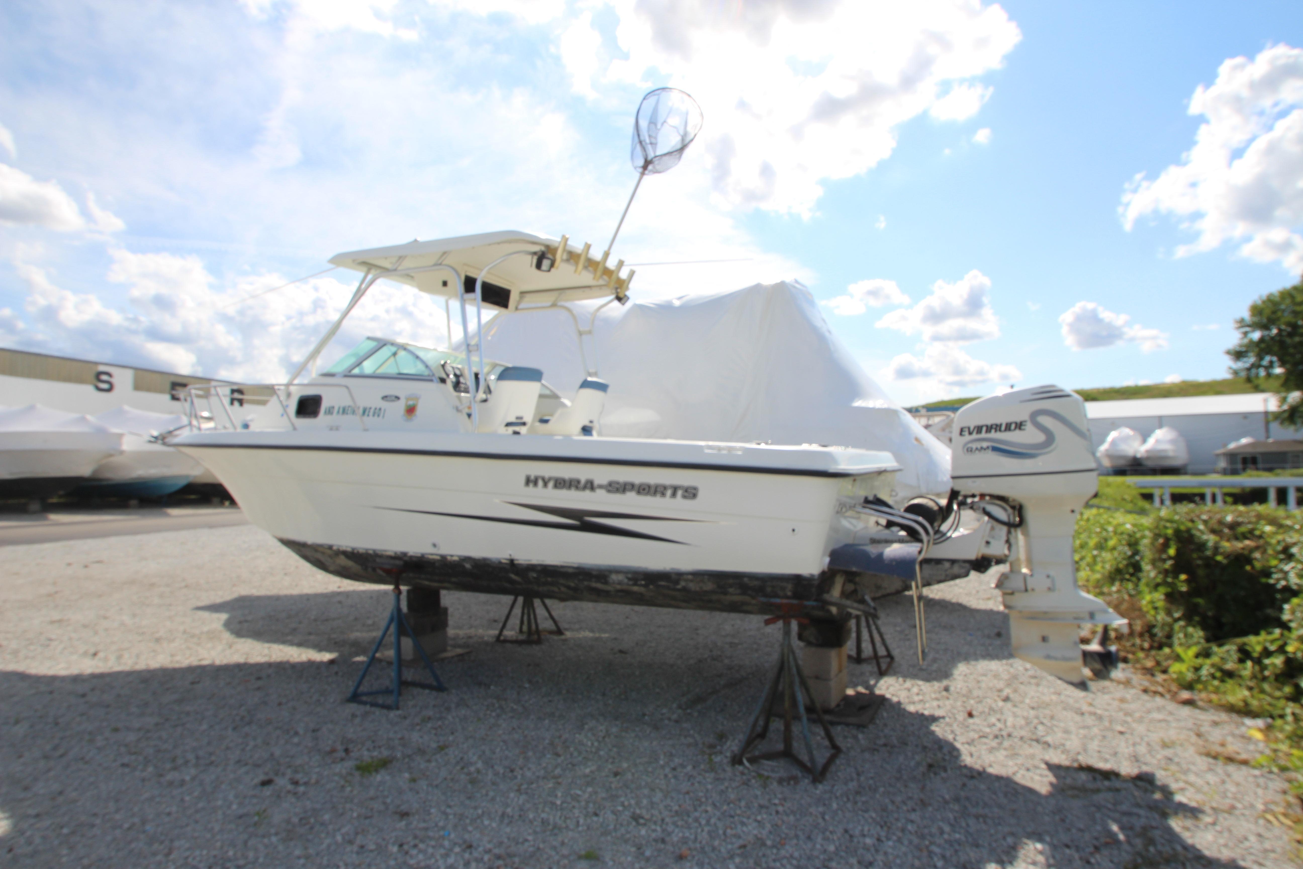 2002 Hydra-Sports 230 WA boat on stands, featuring Evinrude outboard motor, under a bright sky.