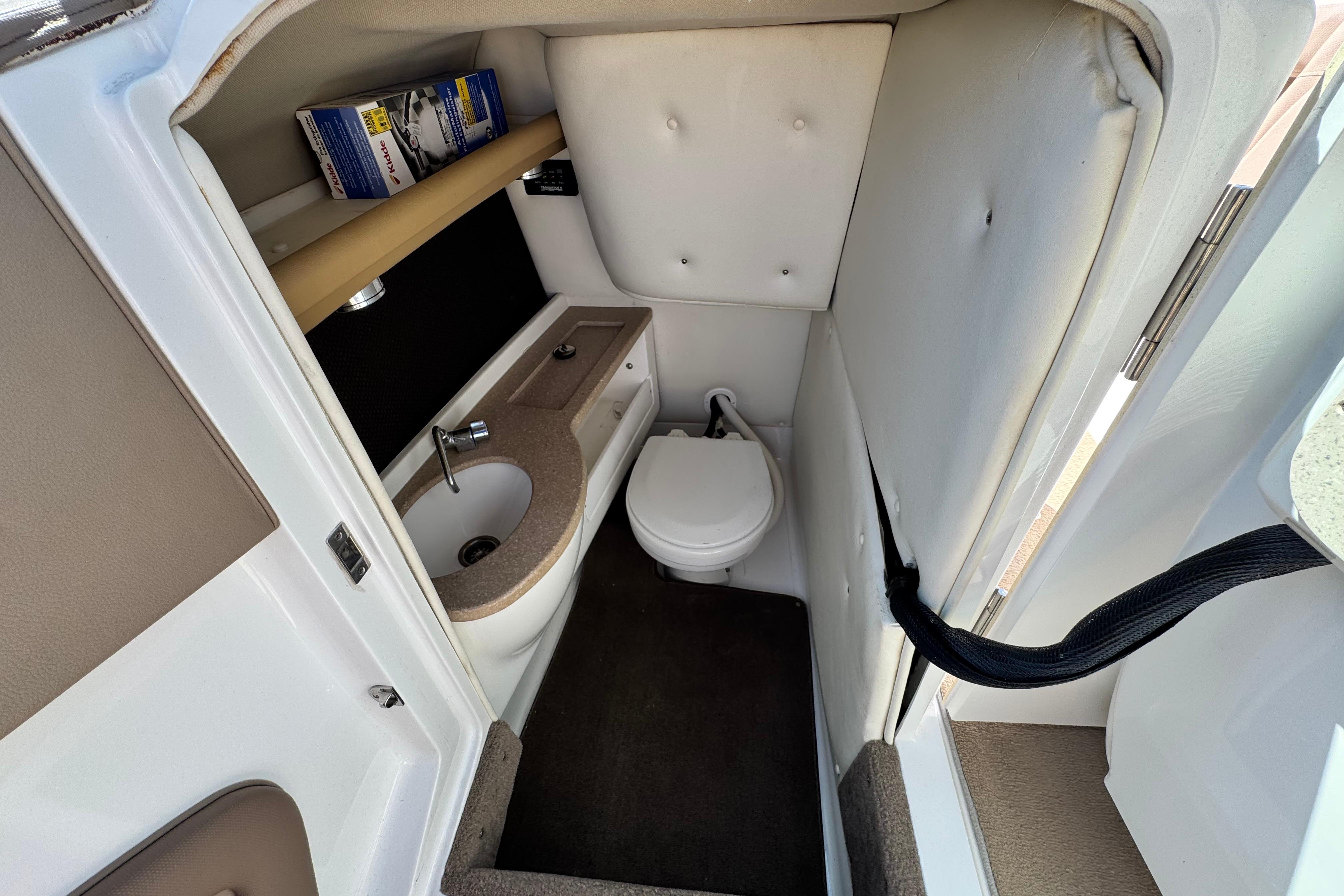 2008 Cobalt 262 boat interior with compact bathroom, sink, and storage shelf.