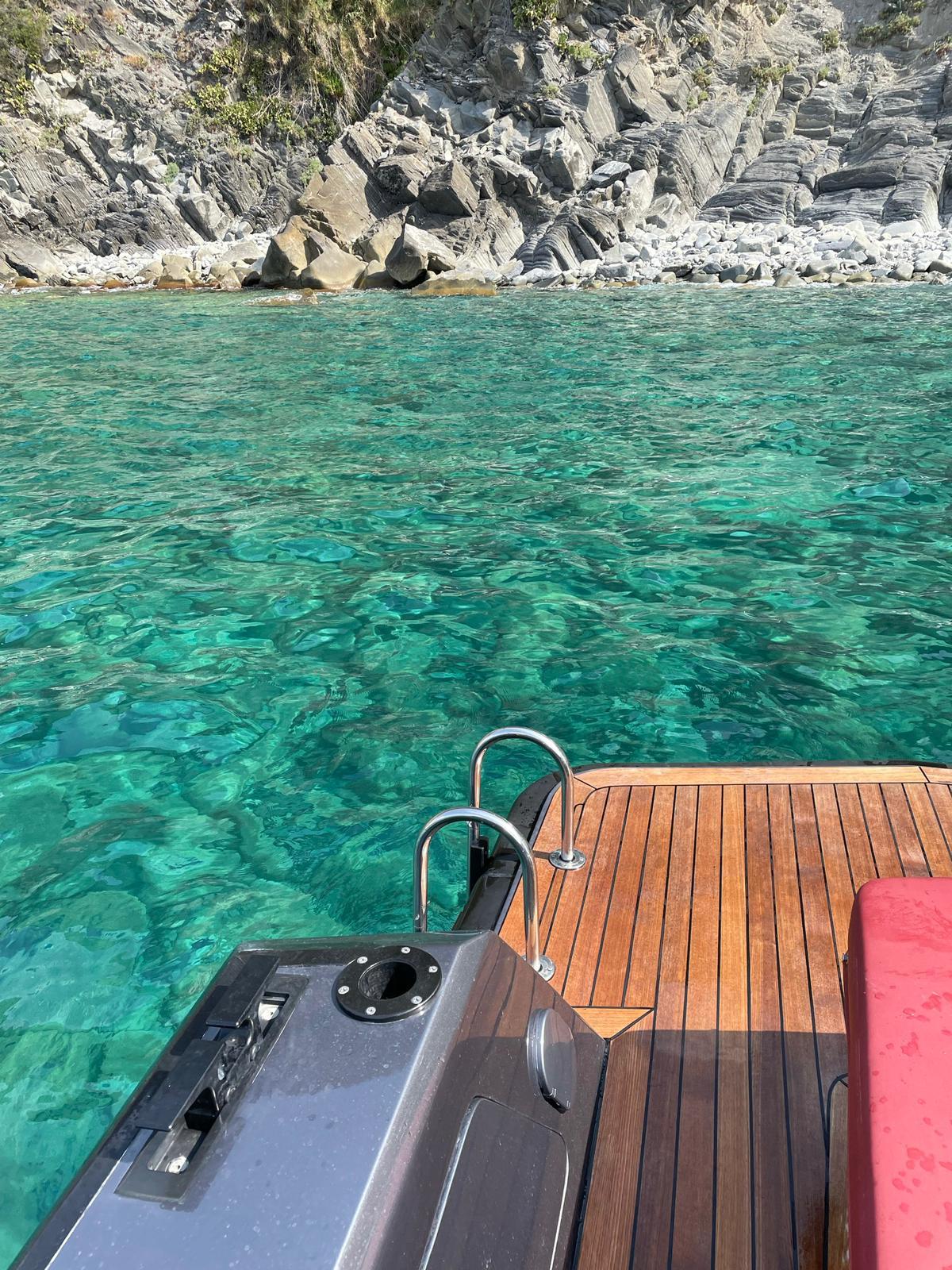 Wallytender 45 yacht deck overlooking clear turquoise water and rocky shoreline.
