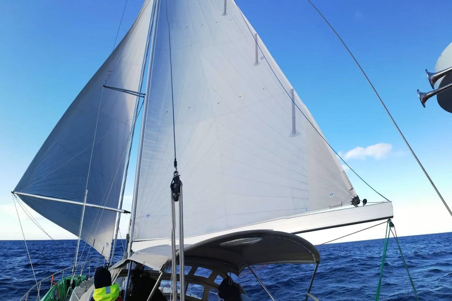 Sailing on a 1990 Kempers 49 yacht with full sails against a clear blue sky.