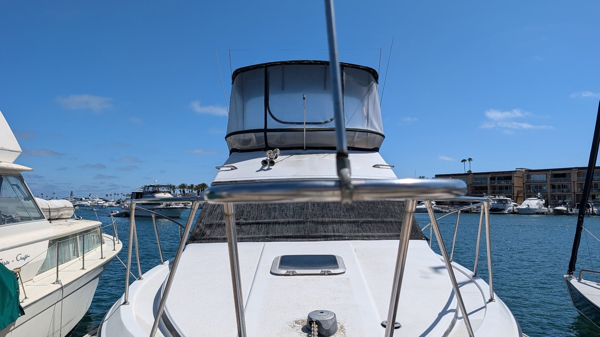 A 1987 Chris-Craft 320 Amerosport Express docked in a marina, surrounded by other boats.