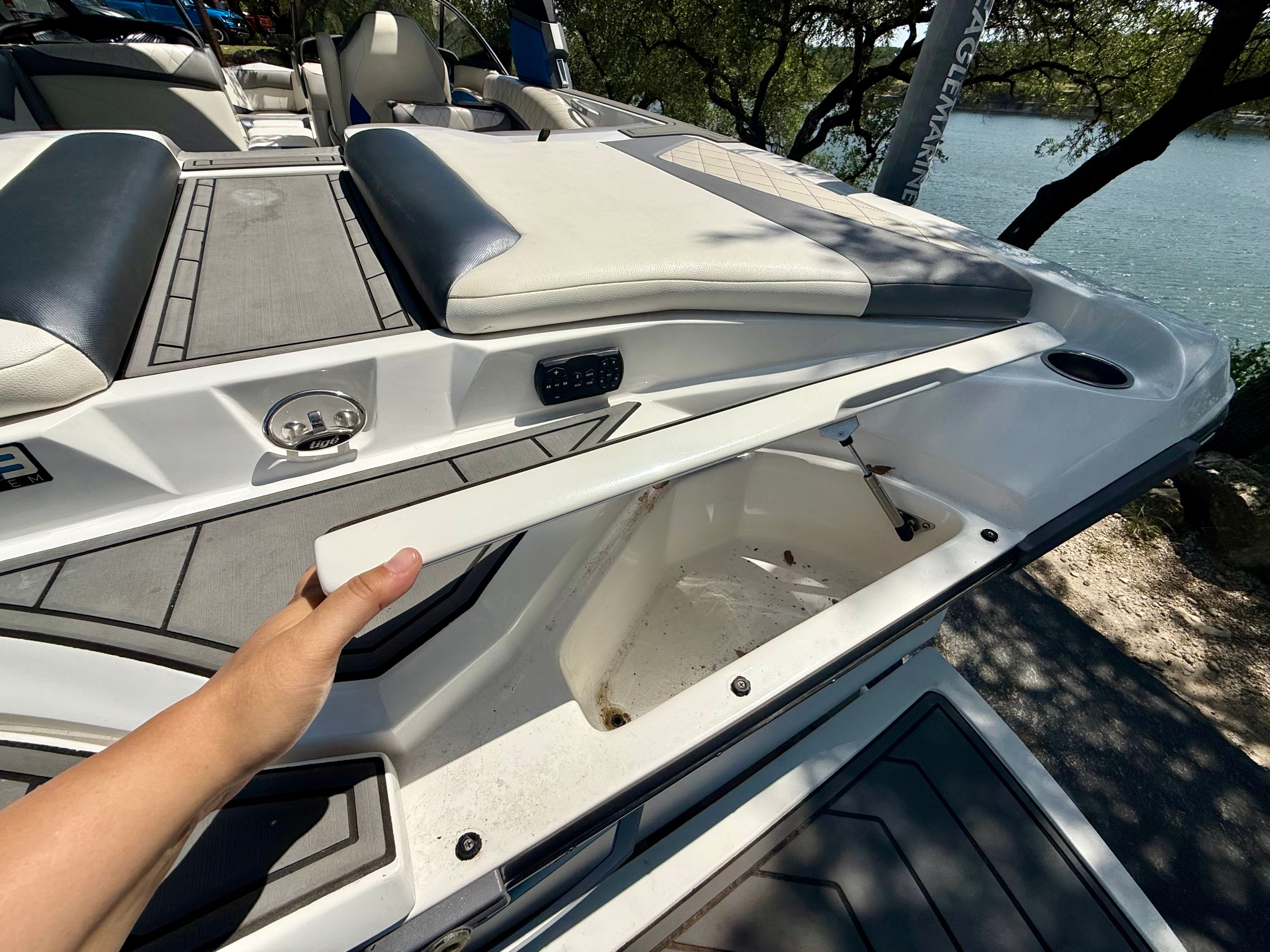 A white boat with gray upholstery and an open storage compartment at the rear.