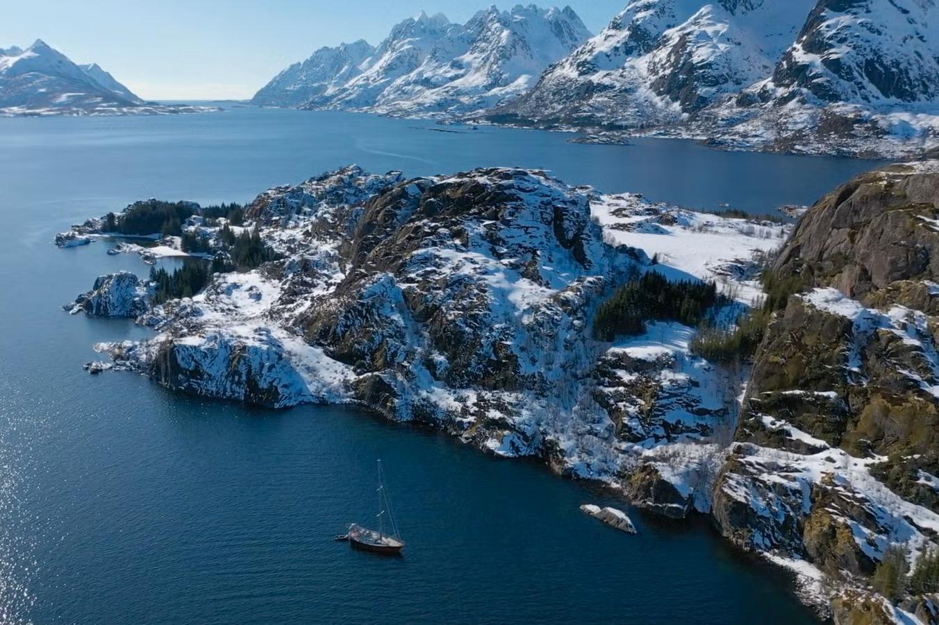 Snowy coastal landscape with a Kempers 49 sailboat, 1990, in a serene fjord setting.