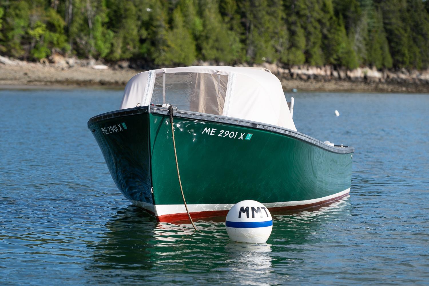 1989 Ellis 24 Open boat moored on calm water with forested shoreline background.