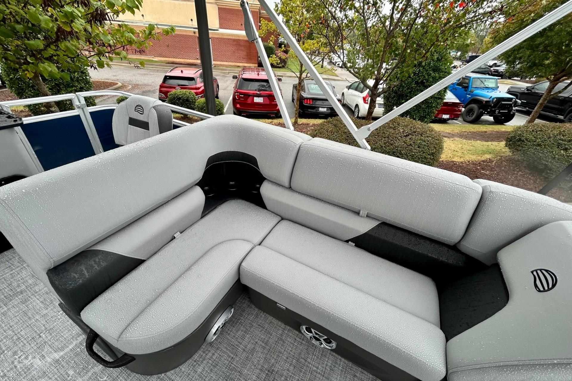 2026 Sun Tracker SportFish 22 DLX pontoon boat with gray seating and outdoor view.