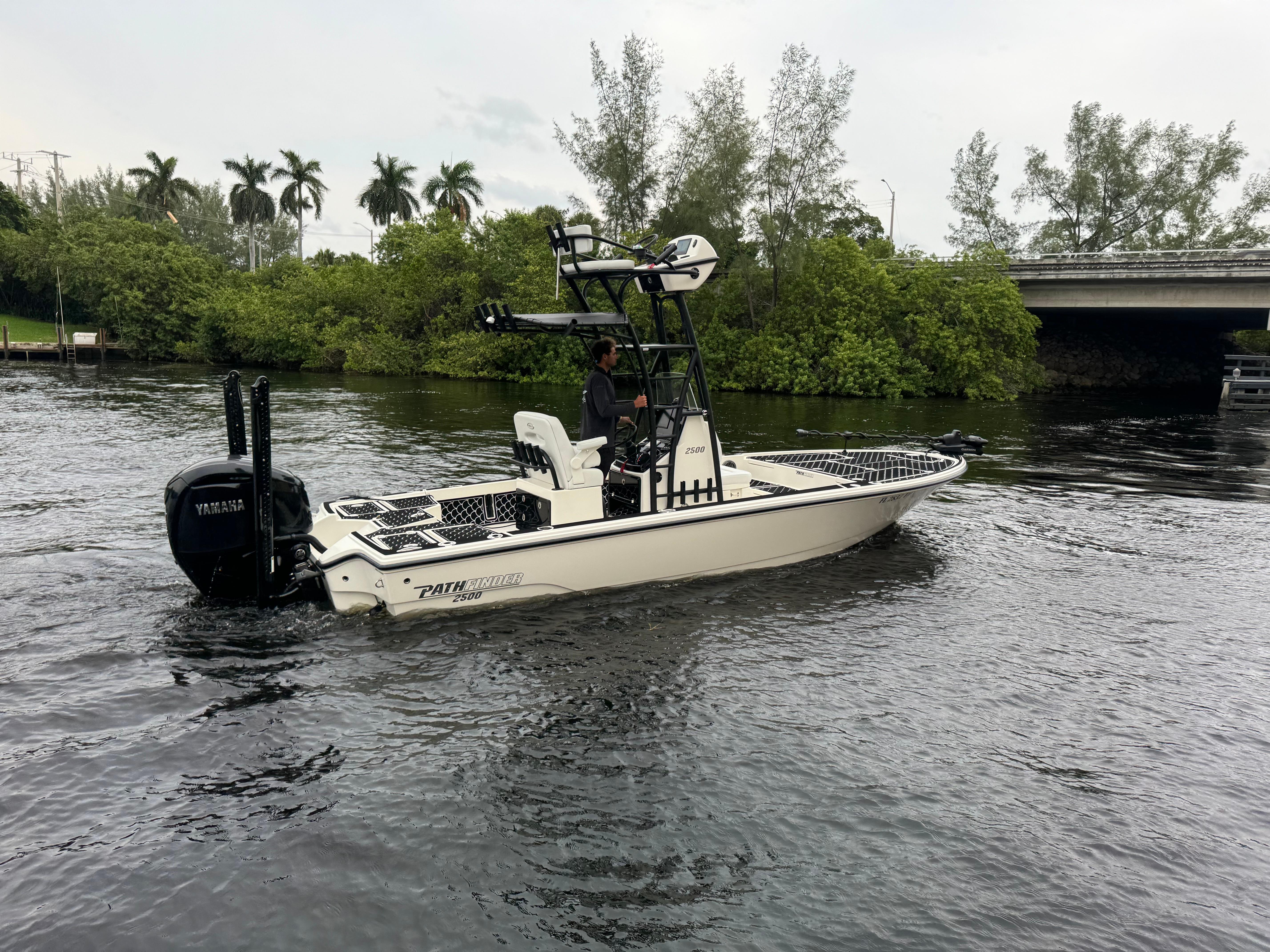 2024 Pathfinder 2500 Hybrid boat cruising on a river near lush greenery.