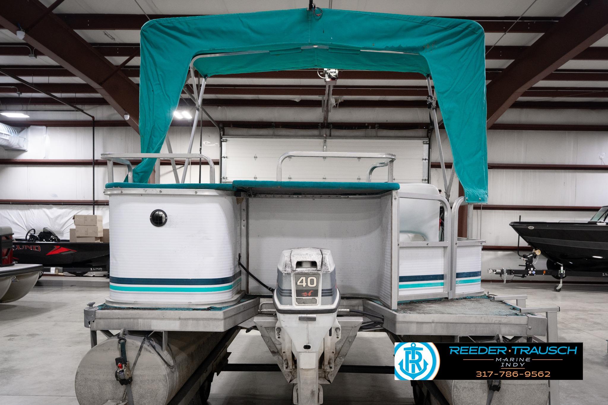1992 Godfrey Sweetwater pontoon boat with teal canopy in indoor storage.