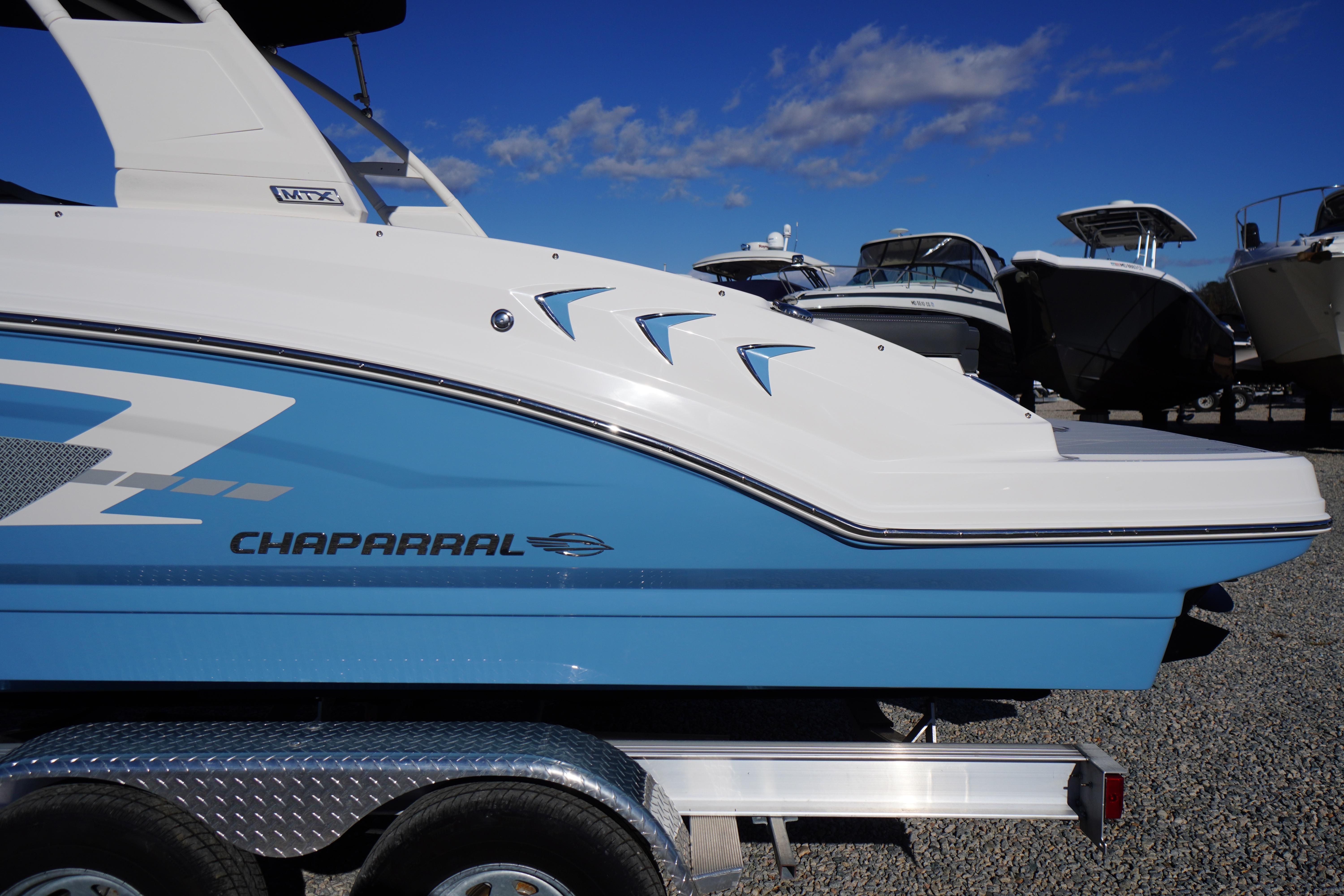 2026 Chaparral 23 SSi boat in blue and white on a trailer under a clear sky.